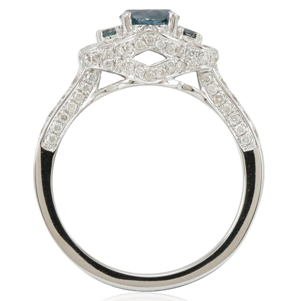 Este magnífico anillo de compromiso único de Suzy Levian es un solitario de 3 diamantes azules con un halo de pavé de diamantes blancos. Elegantemente elaborado en oro blanco de 14 quilates, este anillo presenta una piedra central de diamante azul