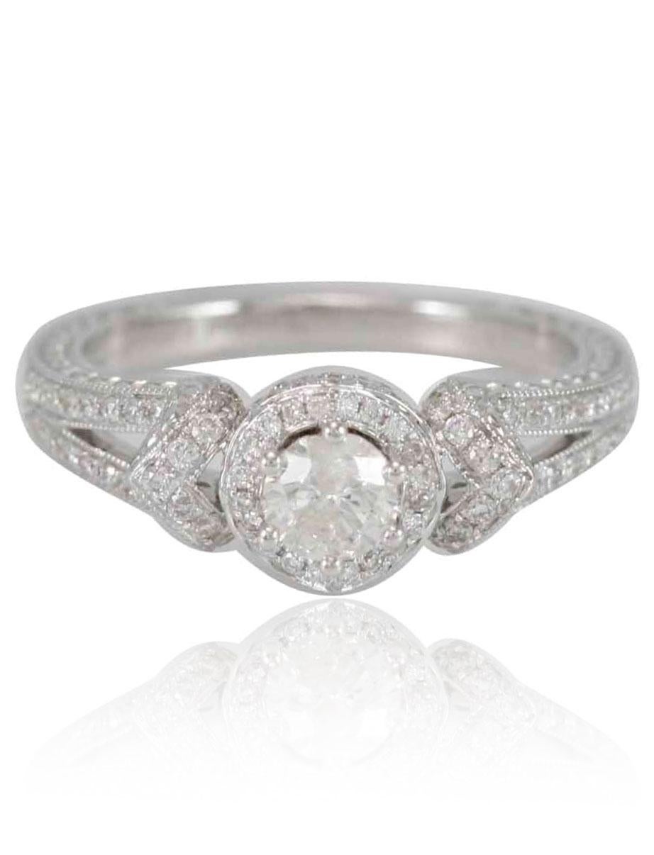 A round-cut 4/5ct TDW white diamond is prong-set atop this lovely engagement ring, featuring a halo of smaller stones around the center. Crafted of 18k white gold, this ring has diamonds along the polished band for a stunning design.