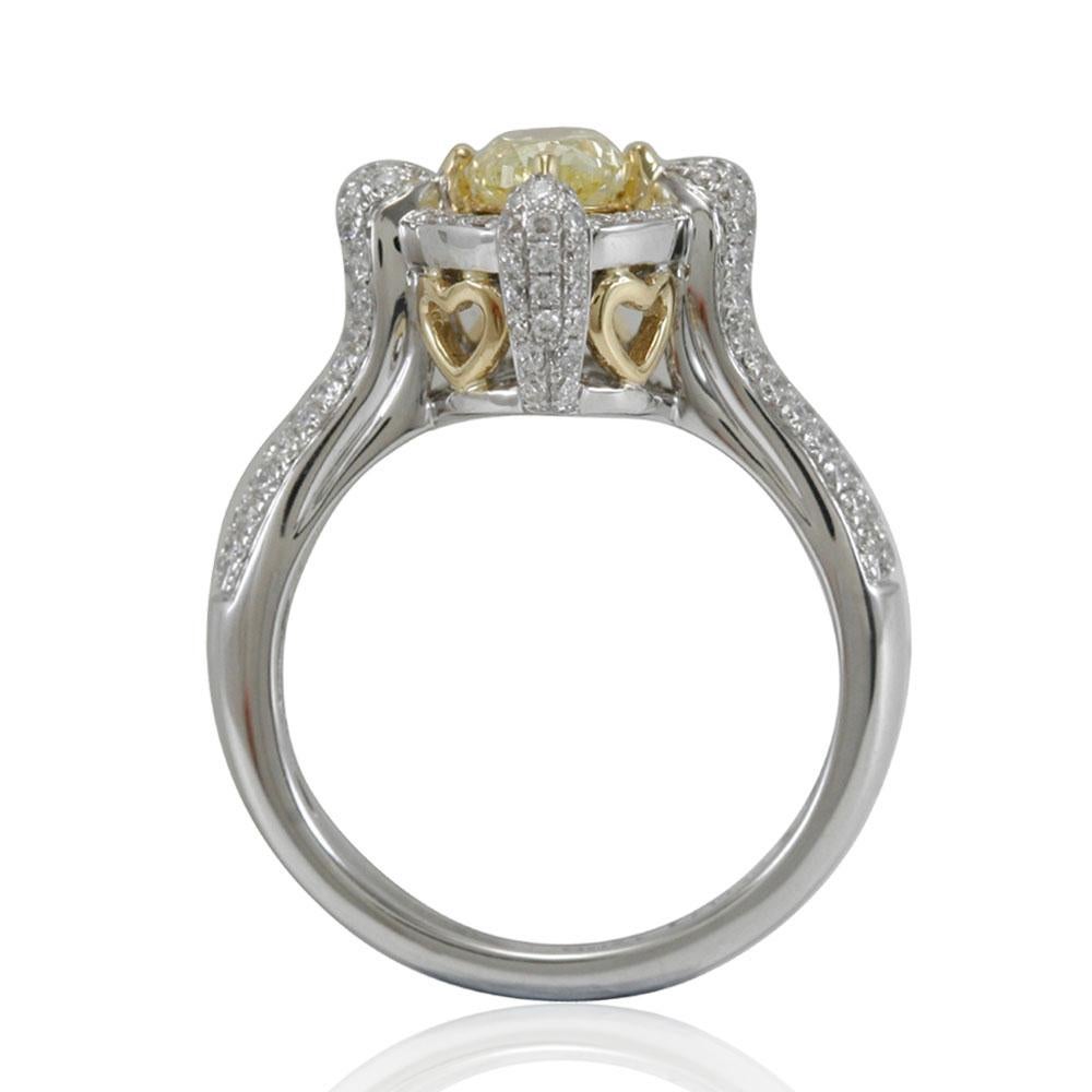 This spectacular ring from the Suzy Levian Limited Edition collection features a gorgeous oval-cut, fancy yellow diamond (1.01 ct) center stone with an array of white diamond (.64 cttw) accents, handset in a 14k two-tone white and yellow gold