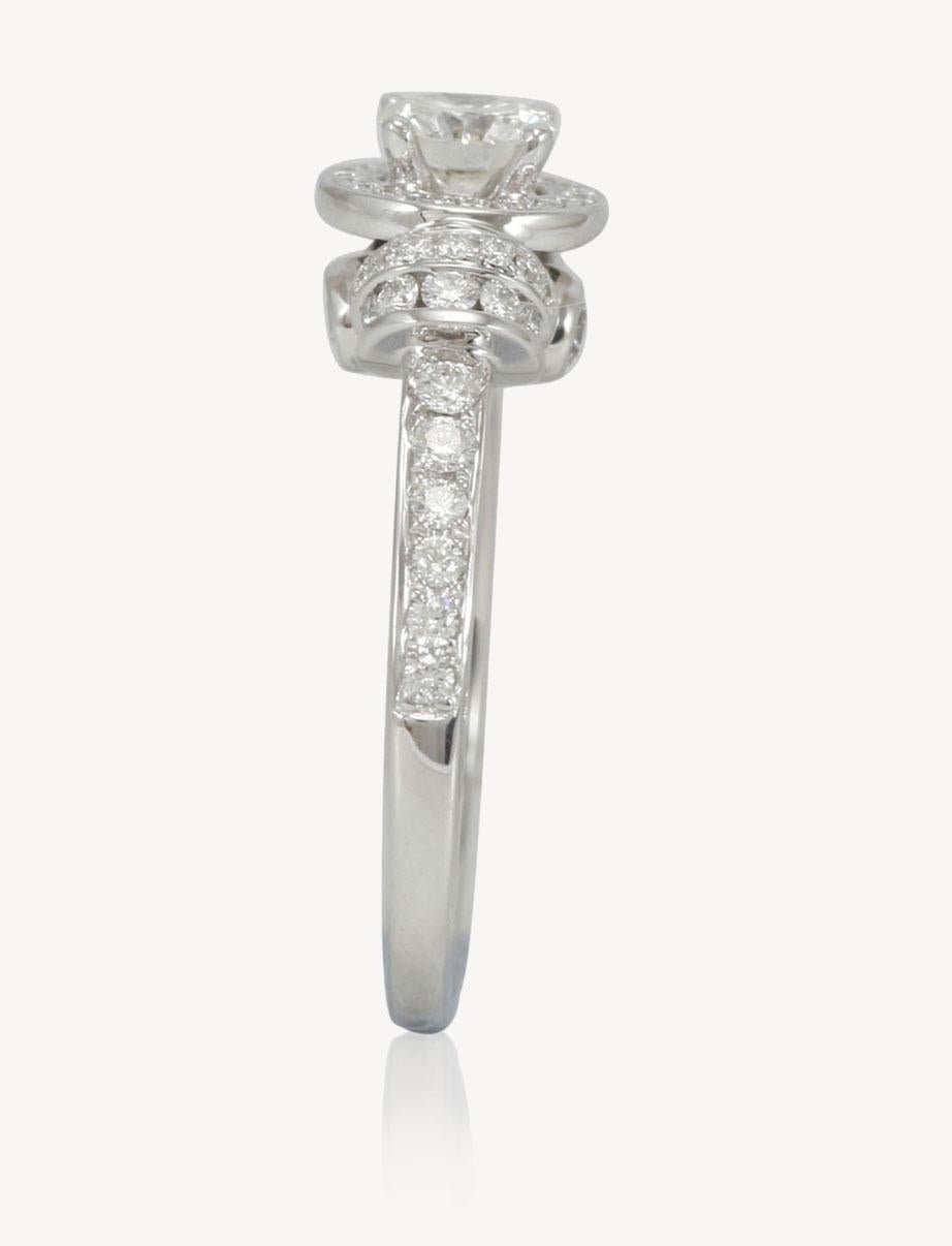 This strikingly gorgeous engagement ring by Suzy Levian is elegantly crafted in 18 karat white gold featuring a GIA certified round brilliant diamond center stone (0.55ct). Placed in a vintage halo setting, this diamond center stone is surrounded by
