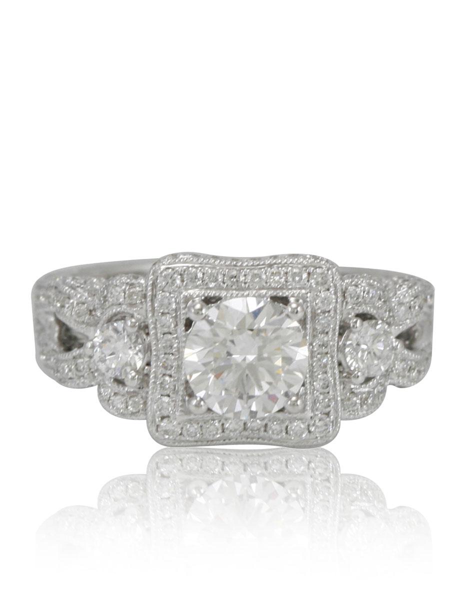 This spectacular Suzy Levian ring features a round-cut diamond (1.04ct) center stone with an array of white diamond (1.00cttw) accents, handset in a 18k white gold setting. French filigree hand-work carves impeccable detail and beautiful depth