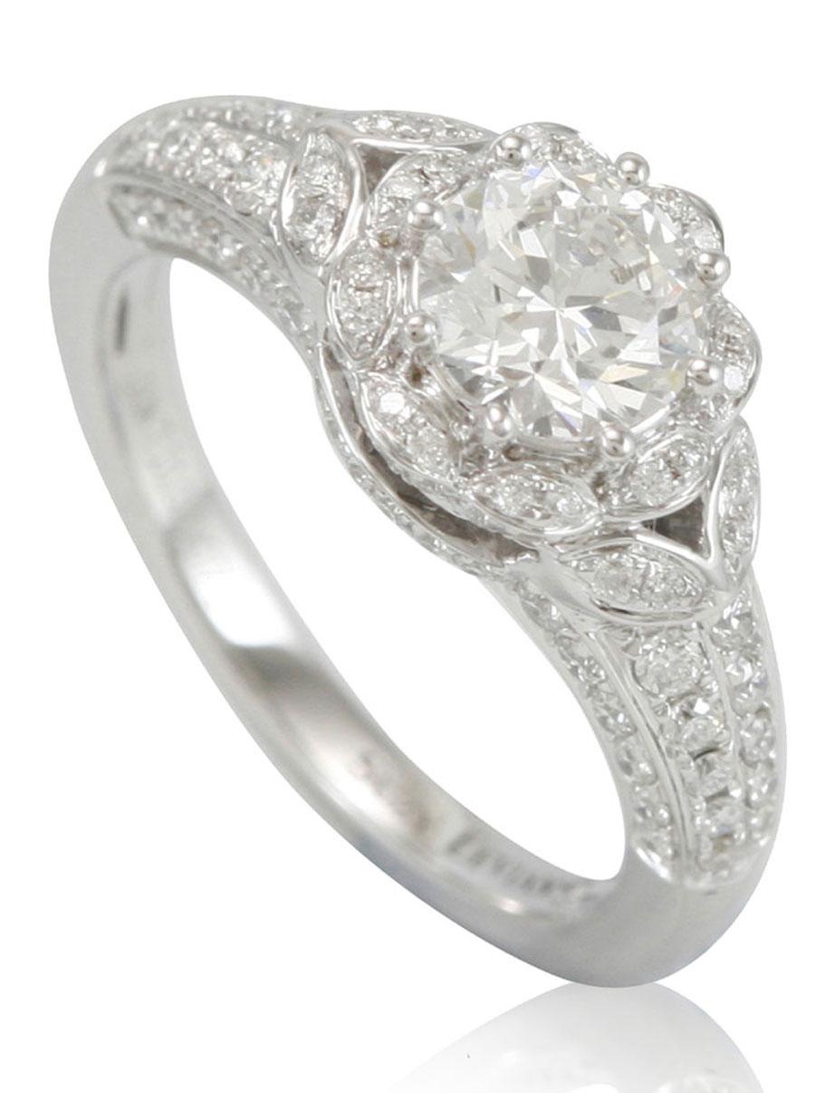 This spectacular Suzy Levian ring features a gorgeous round-cut, fancy white diamond (1.01ct) (H-I, I2) center stone with an array of white diamond (.71cttw) accents, handset in a 18k white gold setting. French filigree hand-work carves impeccable