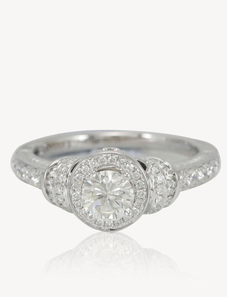 This strikingly gorgeous engagement ring by Suzy Levian is elegantly crafted in 18 karat white gold featuring a GIA certified round brilliant diamond center stone. Placed in a vintage halo setting, this diamond center stone is surrounded by