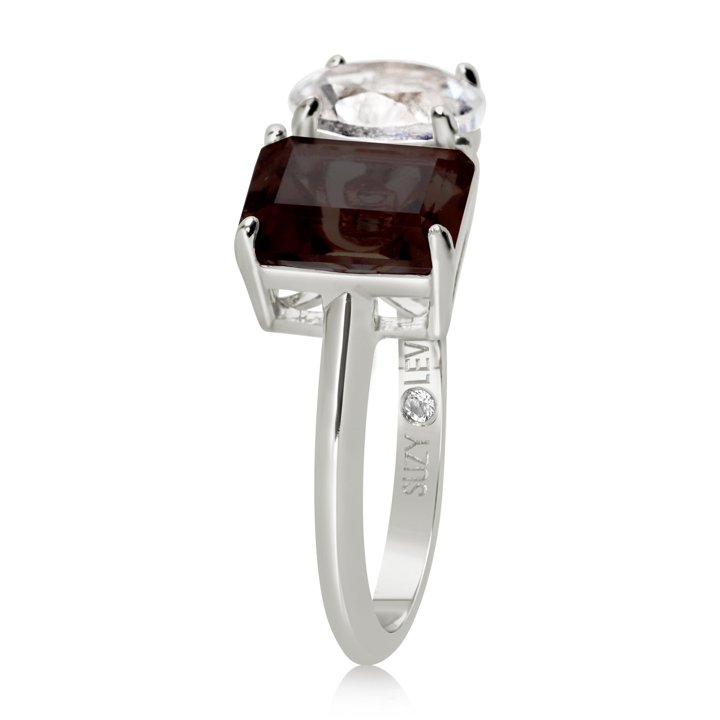 Shimmering in hues of white and brown, this Suzy Levian ring is as on trend as can be, and features a round cut white topaz and an emerald cut smoky quartz as a perfectly matched pair. This ring symbolizes a perfect pairing of unique shapes. This