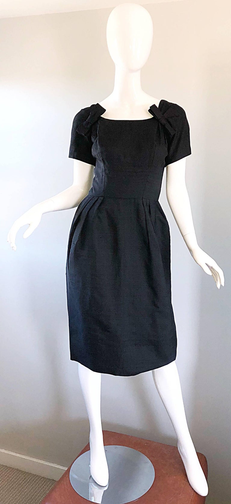 Gorgeous 1950s SUZY PERETTE black silk shantung short sleeve bombshell dress! Features a tailored fitted bodice with a flattering and forgiving full skirt. Bow detail at each side of the neck adds just the right amount of detail. Full metal zipper