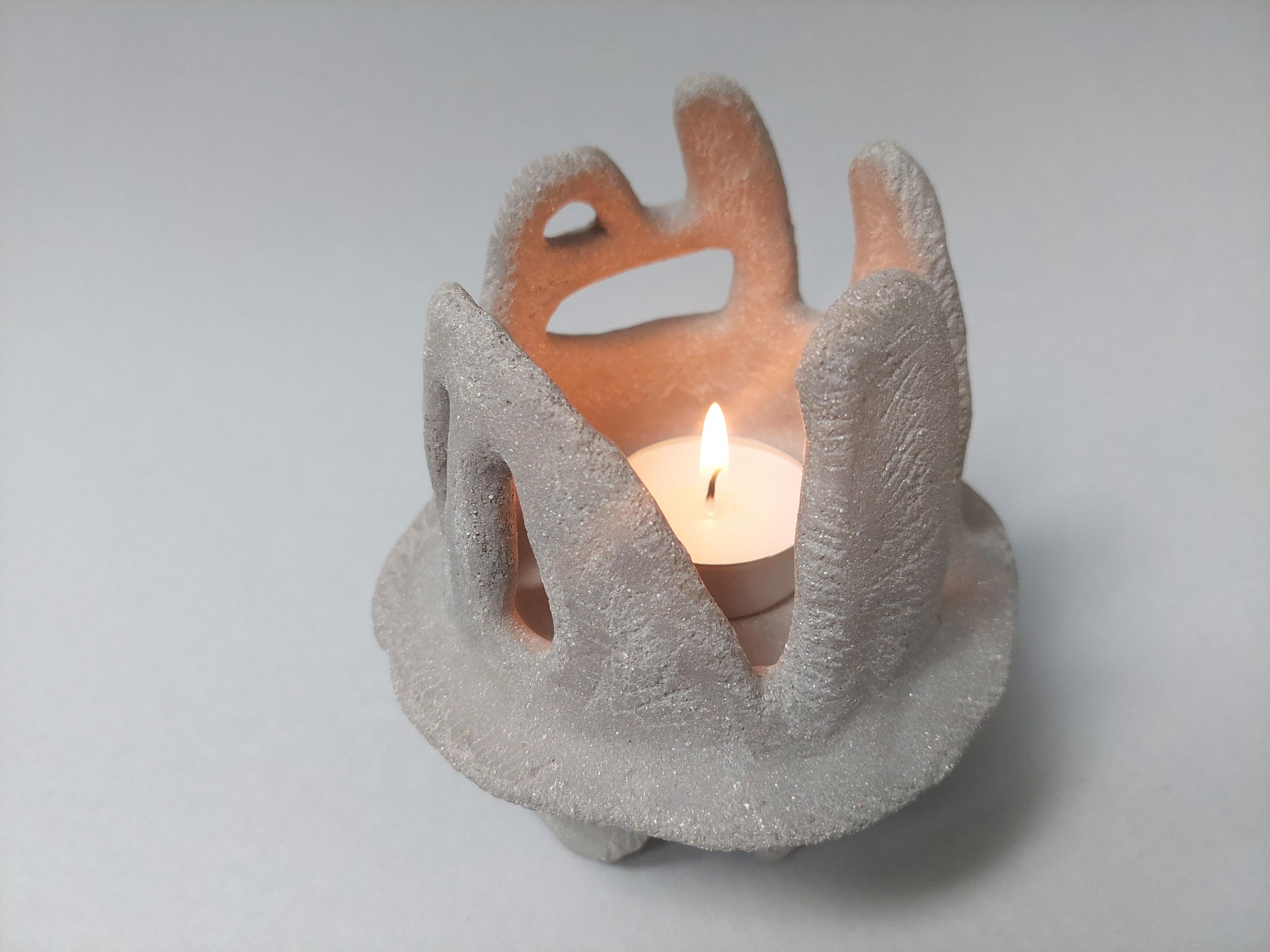 This ceramic sculpture resembles an ancient object. It has a stone texture and rounded plasticity. Inside the sculpture is a place for fire. When the fire burns, the sculpture comes to life. You see a warm light inside and a cold shadow outside. It