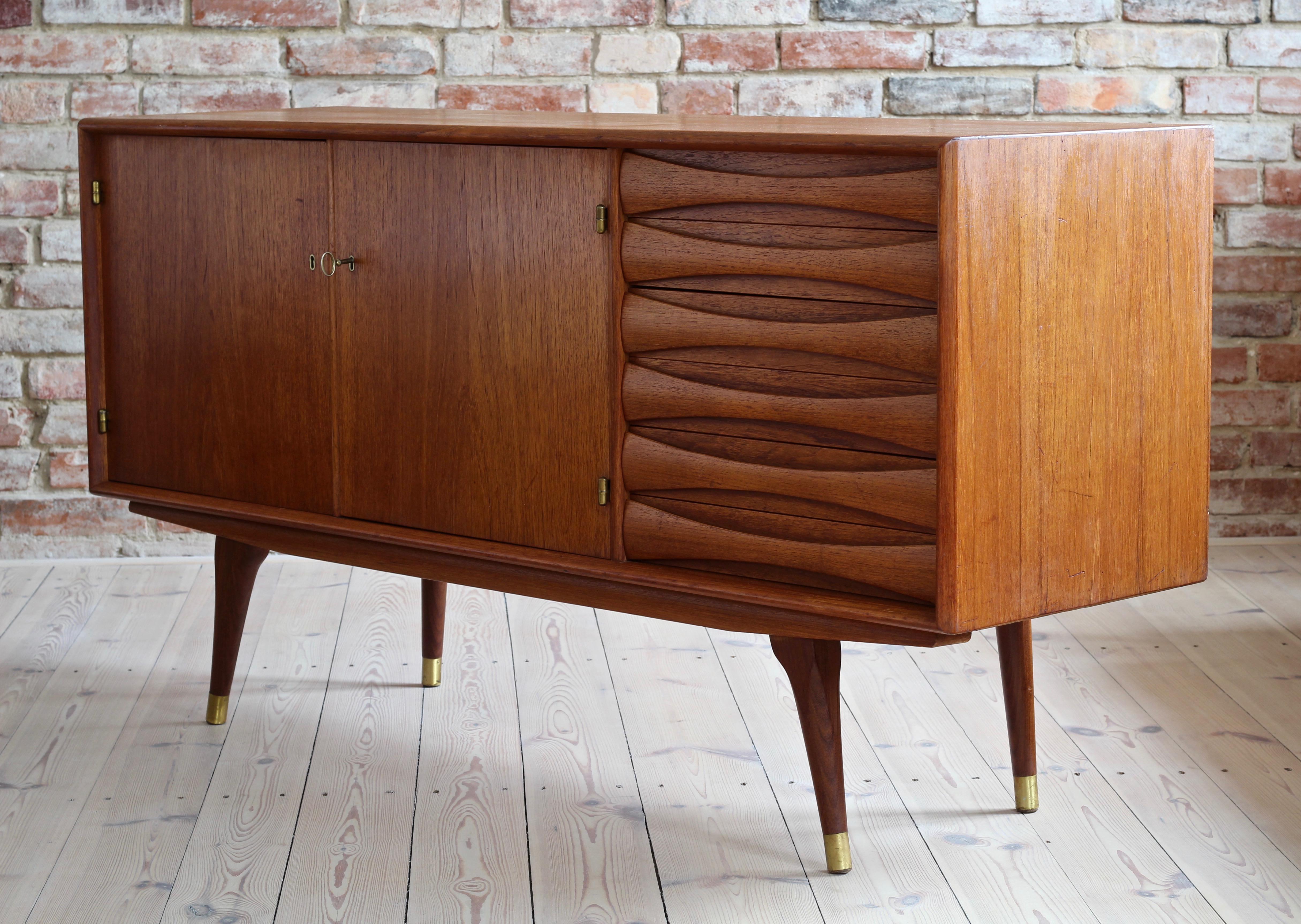 This is a quite rare Sven Andersen teak sideboard designed and manufactured in Norway around second half of 1950s. The piece features two doors that reveal lots of storage space and six drawers in the section on the right. The sideboard features