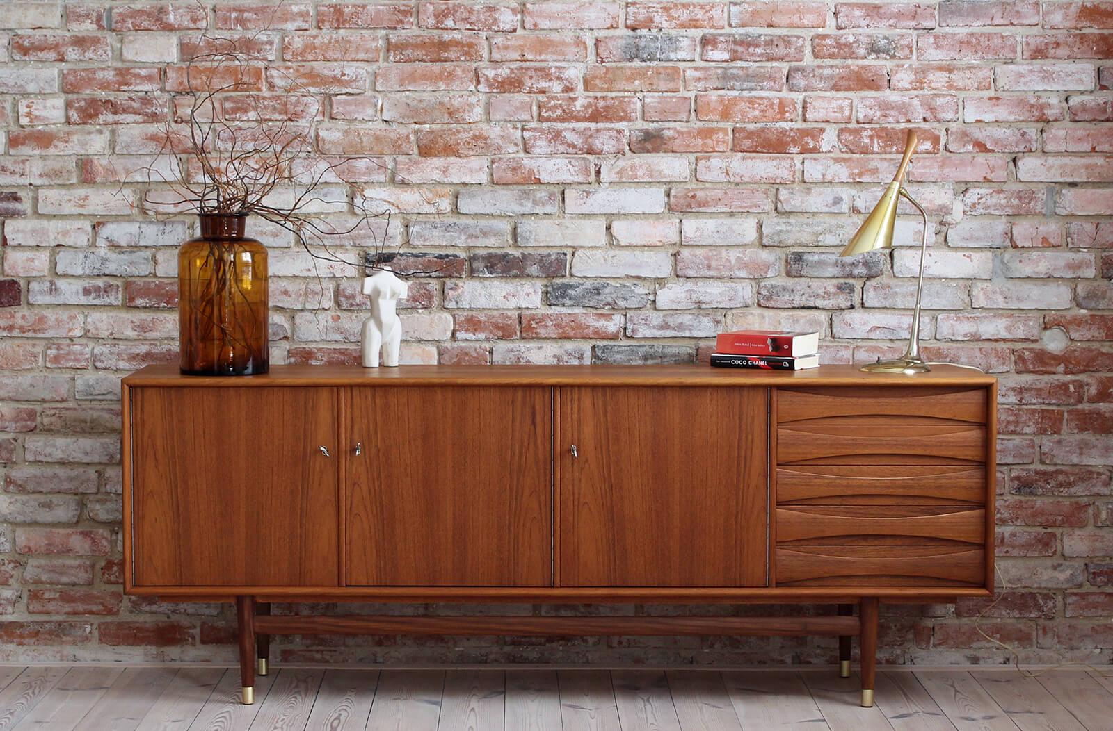 This is a quite rare Sven Andersen teak sideboard designed and manufactured in Norway circa second half of the 1950s. The piece features three doors that reveal lots of storage space and five drawers in the section on the right. The sideboard