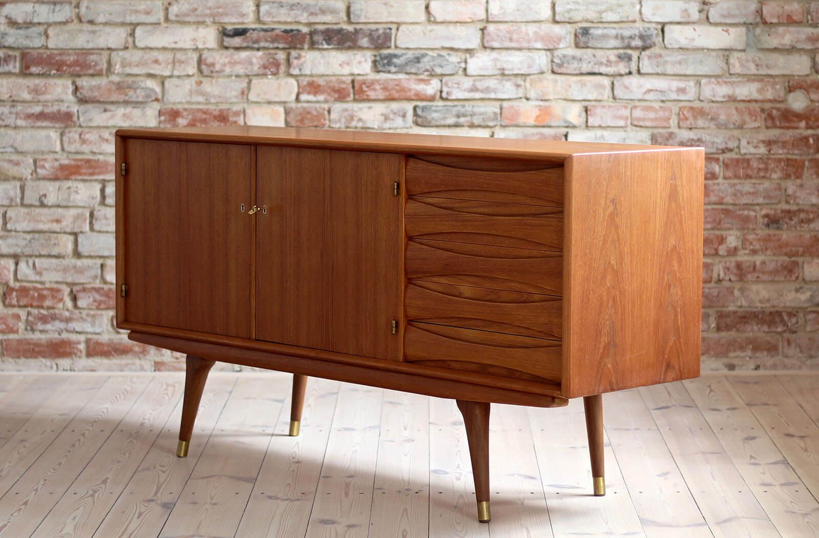 This is a quite rare Sven Andersen teak sideboard designed and manufactured in Norway around second half of 1950s. The piece features two doors that reveal lots of storage space and five drawers in the section on the right. The sideboard features