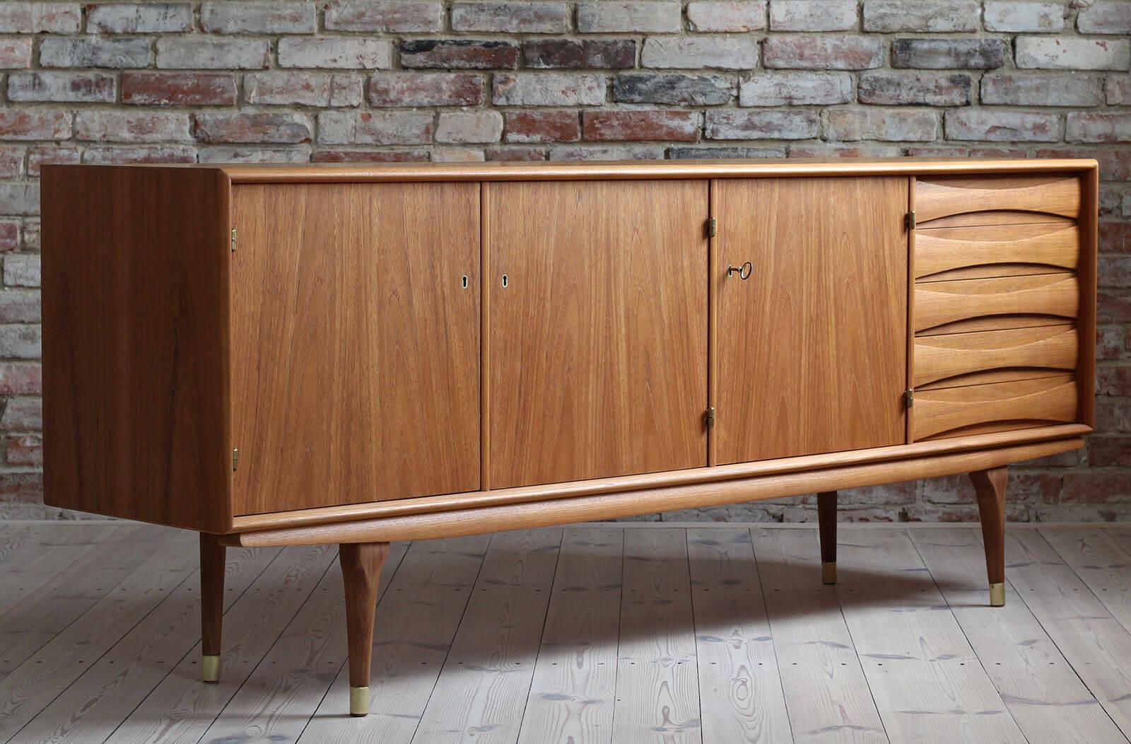 This is a quite rare Sven Andersen teak sideboard designed and manufactured in Norway circa second half of the 1950s. The piece features three doors that reveal lots of storage space and five drawers in the section on the right. The sideboard