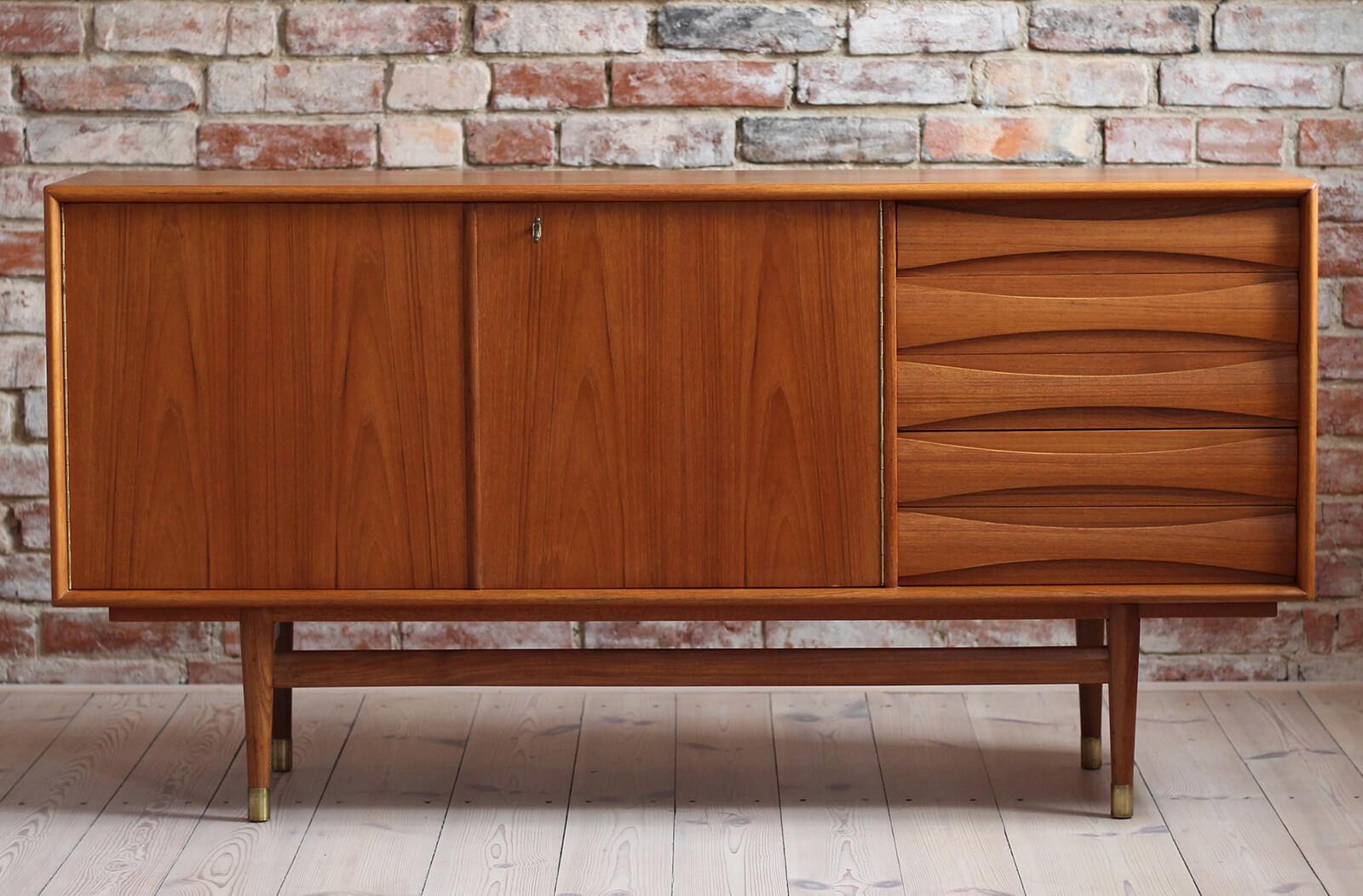 This is a quite rare Sven Andersen teak sideboard designed and manufactured in Norway around second half of 1950s. The piece features two doors that reveal lots of storage space and five drawers in the section on the right. The sideboard features