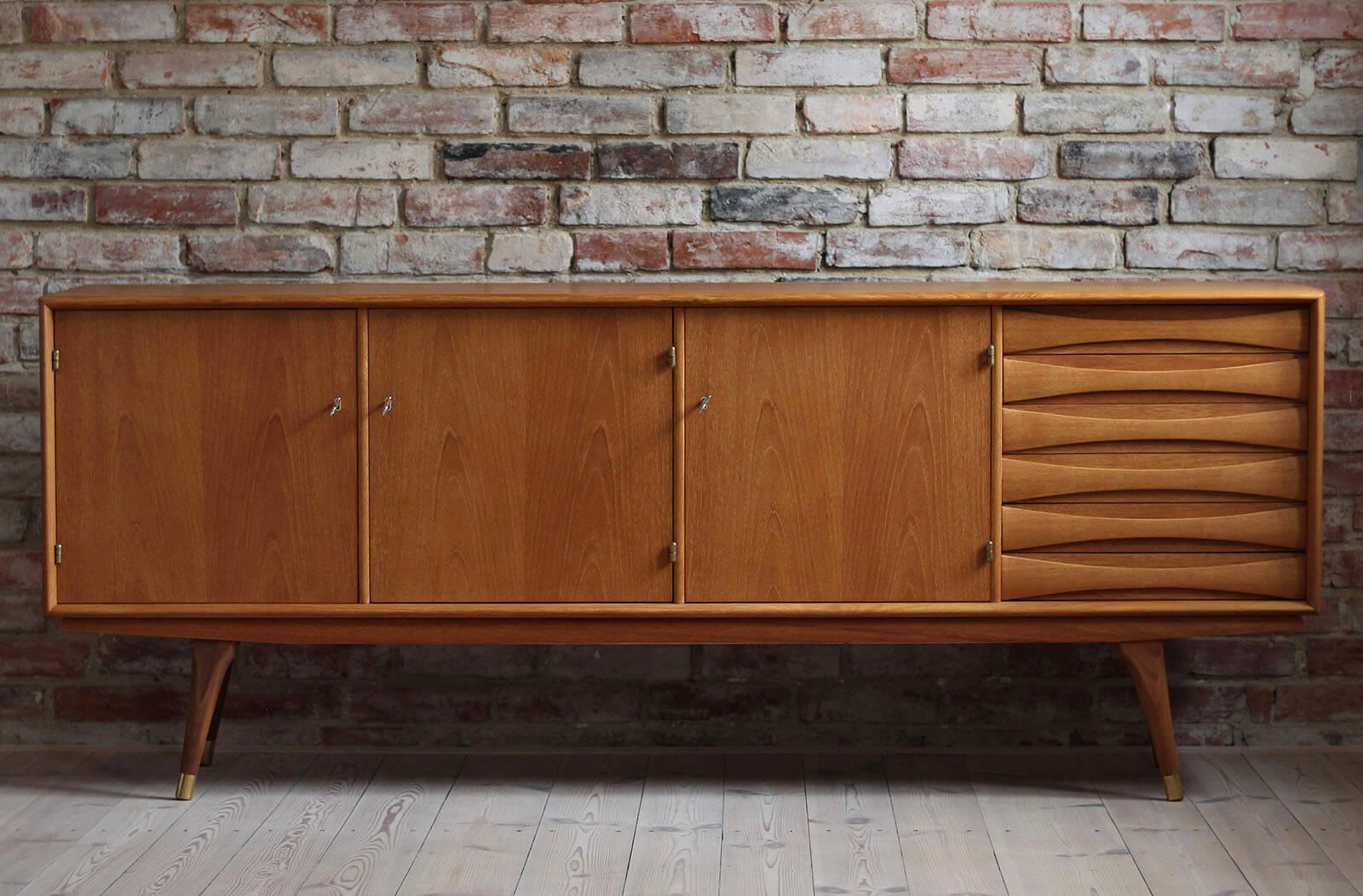 This beautiful teak sideboard was designed by Sven Andersen and manufactured in Norway in second half of the 1950s. The piece features three doors that reveal lots of storage space and six drawers in the section on the right. The sideboard features
