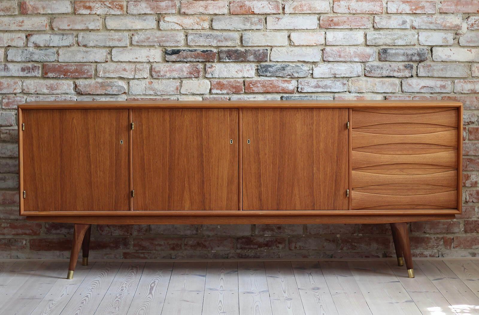 This beautiful teak sideboard was designed by Sven Andersen and manufactured in Norway in second half of the 1950s. The piece features three doors that reveal lots of storage space and five drawers in the section on the right. The sideboard features