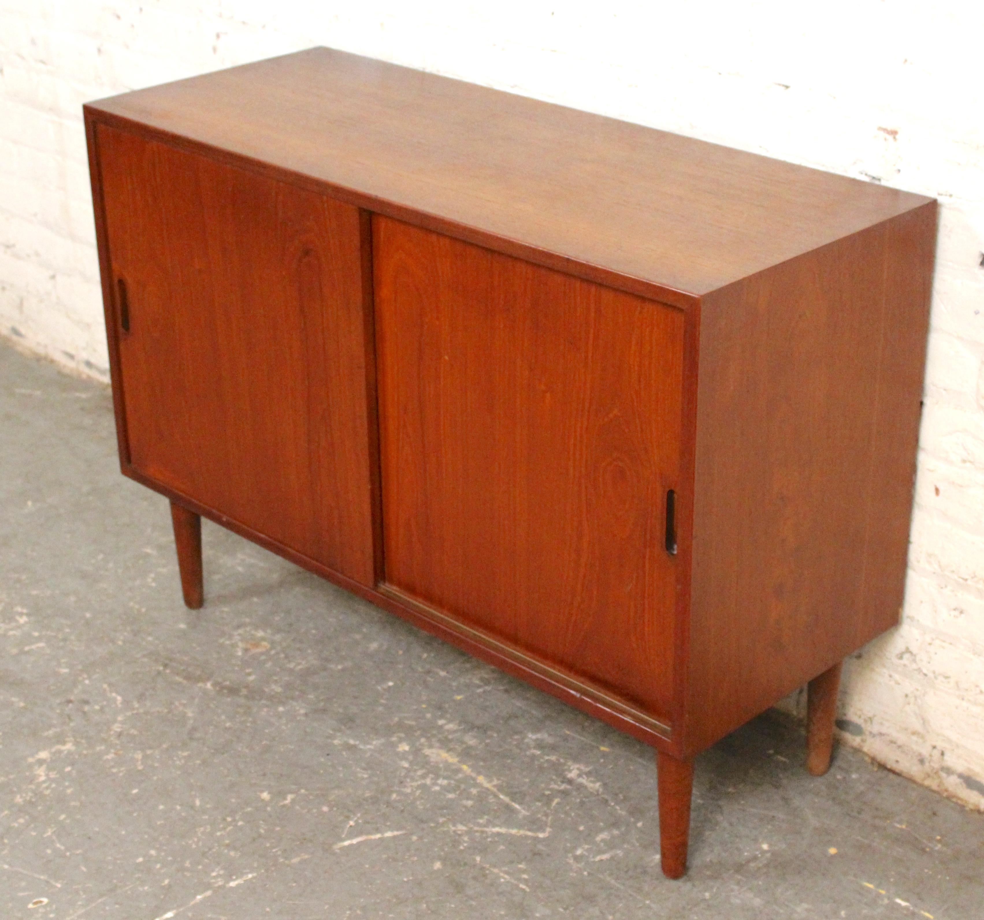 Kleiner Schrank mit Schiebetüren aus Teakholz, mit eingelassenen Holzgriffen und konisch zulaufenden Beinen. Entworfen von Sven Ellekaer für Albert Hansen für Raymor. Inklusive Rückwandhalterungen für die Wandmontage.
Bitte bestätigen Sie den