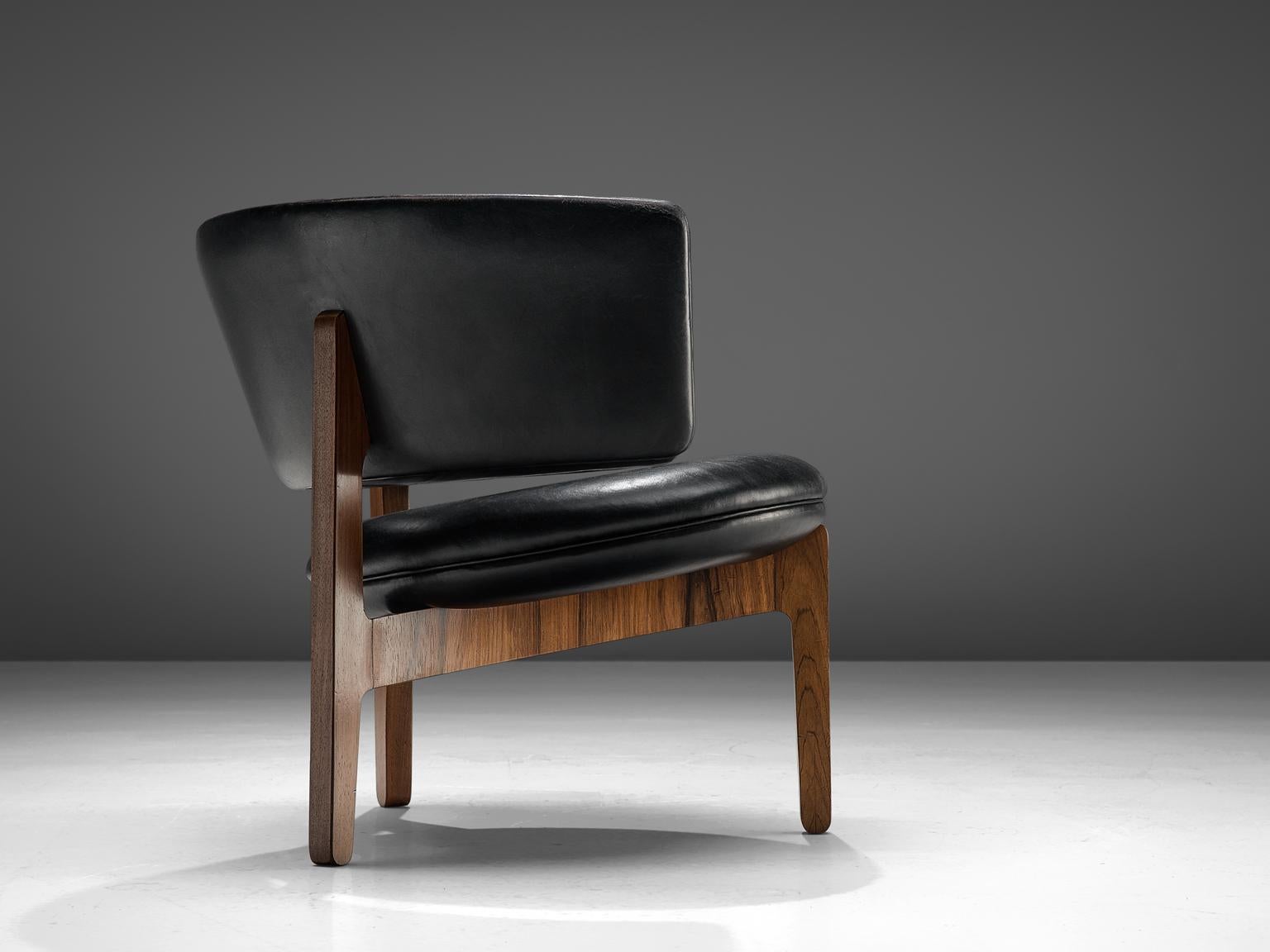 Sven Ellekaer for Christian Linnenberg's Møbelfabrik, lounge chair in rosewood and black leather, Denmark, design 1962.

This piece, featuring a semi-circular back was designed in 1962 together with a small range of accompanying furniture. The