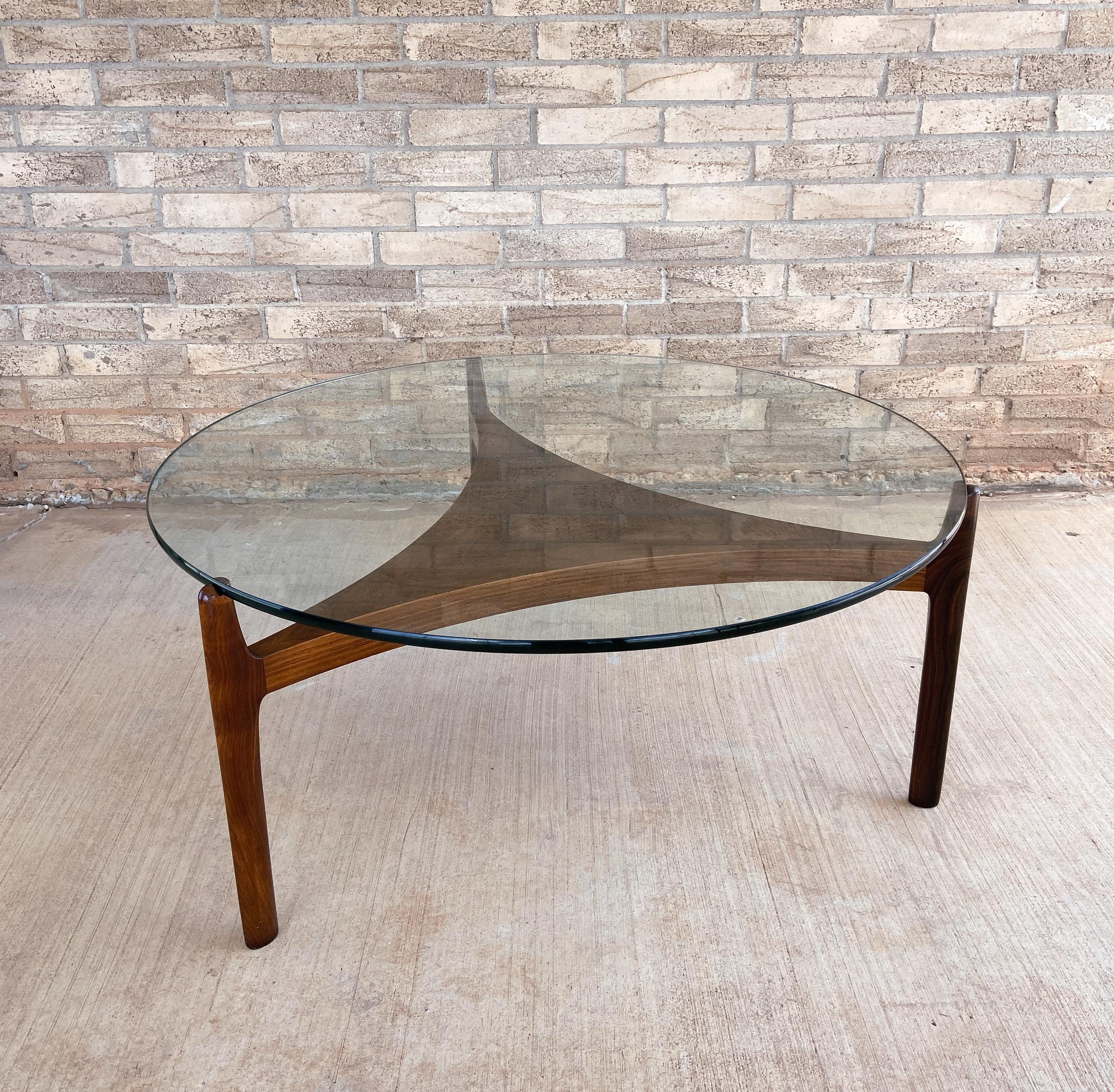 Offered is a lovely, sculpted rosewood coffee/cocktail table designed by Sven Ellekaer and manufactured by Christian Linneberg.

Featuring solid rosewood legs that have stunning grain throughout. There are sculpted notches where the glass rest