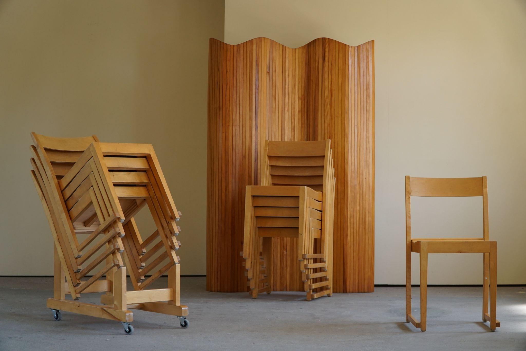 Set of ten dining chairs in birch designed by the Swedish architect Sven Markelius. All chairs are stackable and comes with the original rack. 
Produced by Bodafors for the Helsingborg Concert Hall in 1932, here by the nickname 