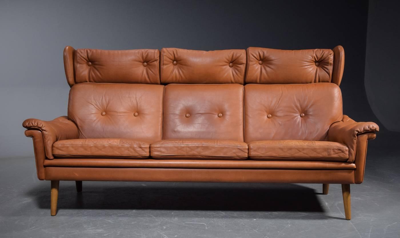 Rare to find super charming coupe sofa designed bu Sven Skipper and made by Skipper's Furniture in Denmark late 1960s. Supple cognac colored leather raised on oak legs. The coupe design were more popular in the 1930s as exemplified by some of Kaare