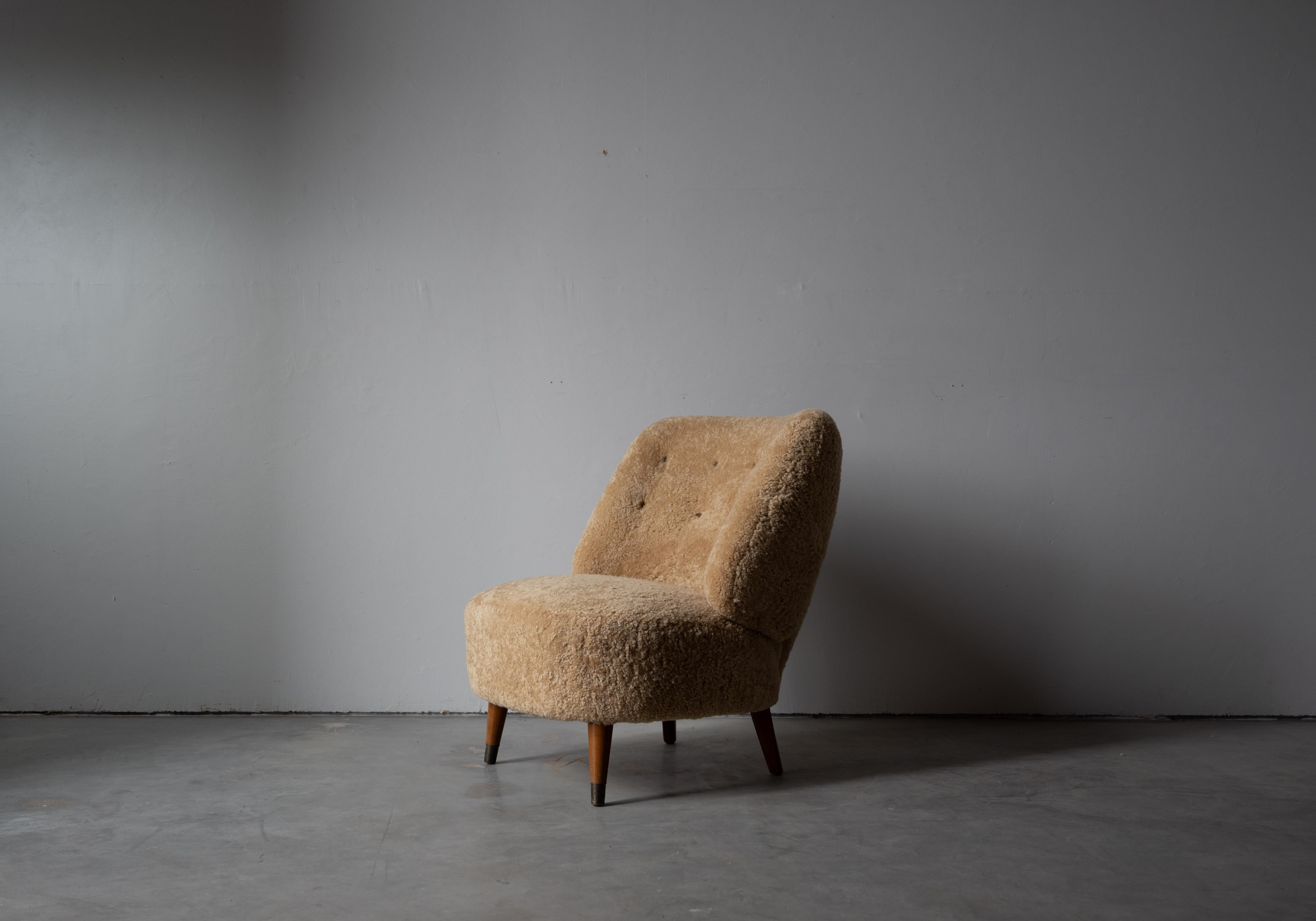 A beige shearling and wood lounge chair designed and produced by Sven Staaf, Sweden, 1940s.
