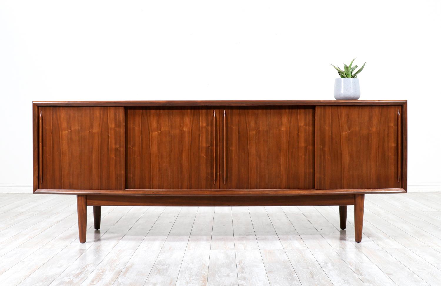 An impressive Scandinavian credenza designed by Svend A. Madsen in collaboration with the workshop of H.P. Hansen in Denmark during the 1960s. This gorgeous design features a walnut wood curved front case with four dovetailed drawers and ample