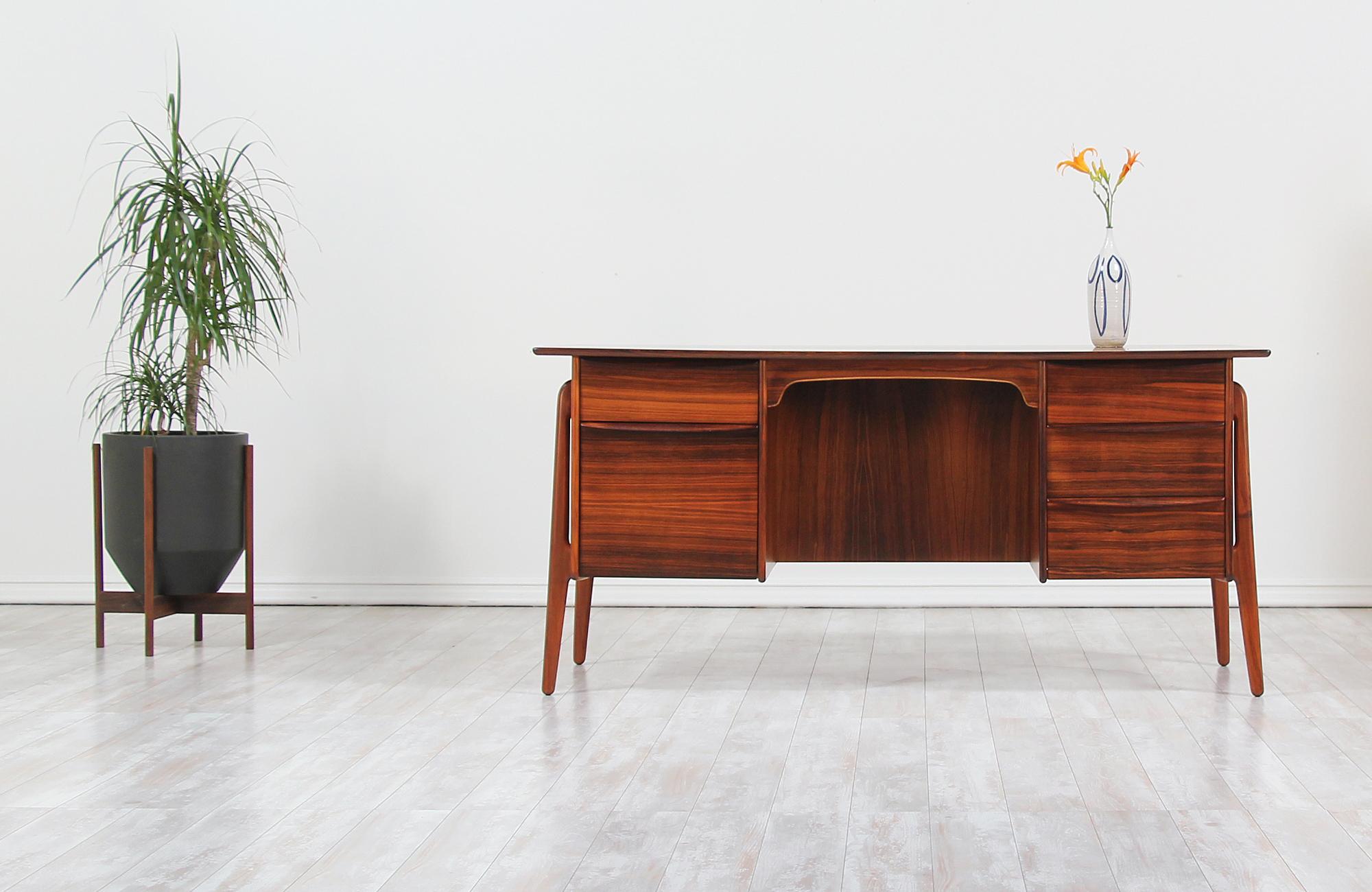 Versatile Danish modern executive desk designed by Svend A. Madsen for Sigurd Hansen in Denmark, circa 1950s. This Classic and elegant Danish desk features a sturdy Brazilian rosewood frame with a stunning grain detail throughout and four sculpted