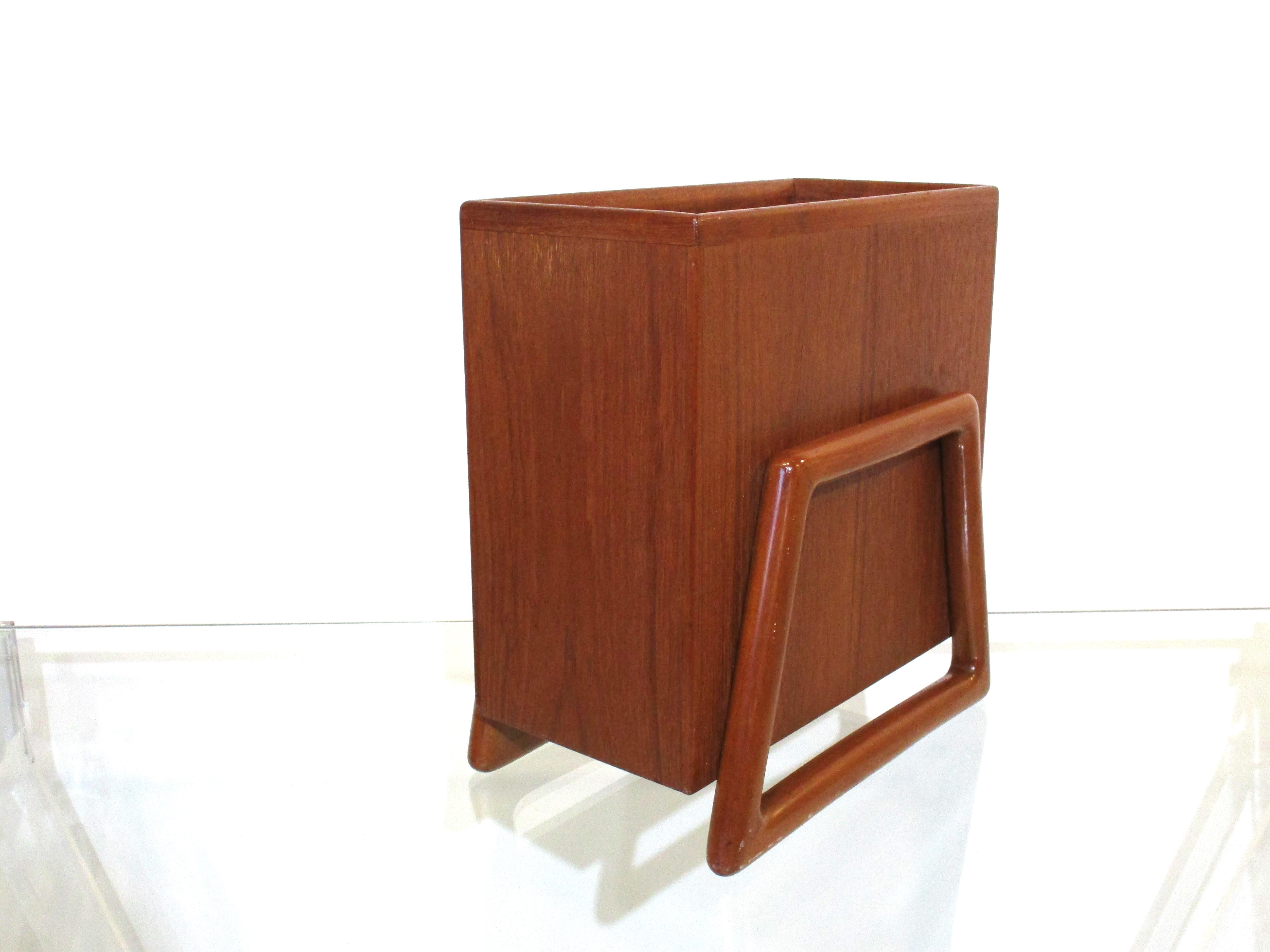 A very well crafted solid teak wood waste basket or magazine rack with stirrup styled legs a hallmark of the designer Svend Aage Madsen. Produced in 1962 and put into climate controlled storage since 1975 when removed for our ownership. The piece