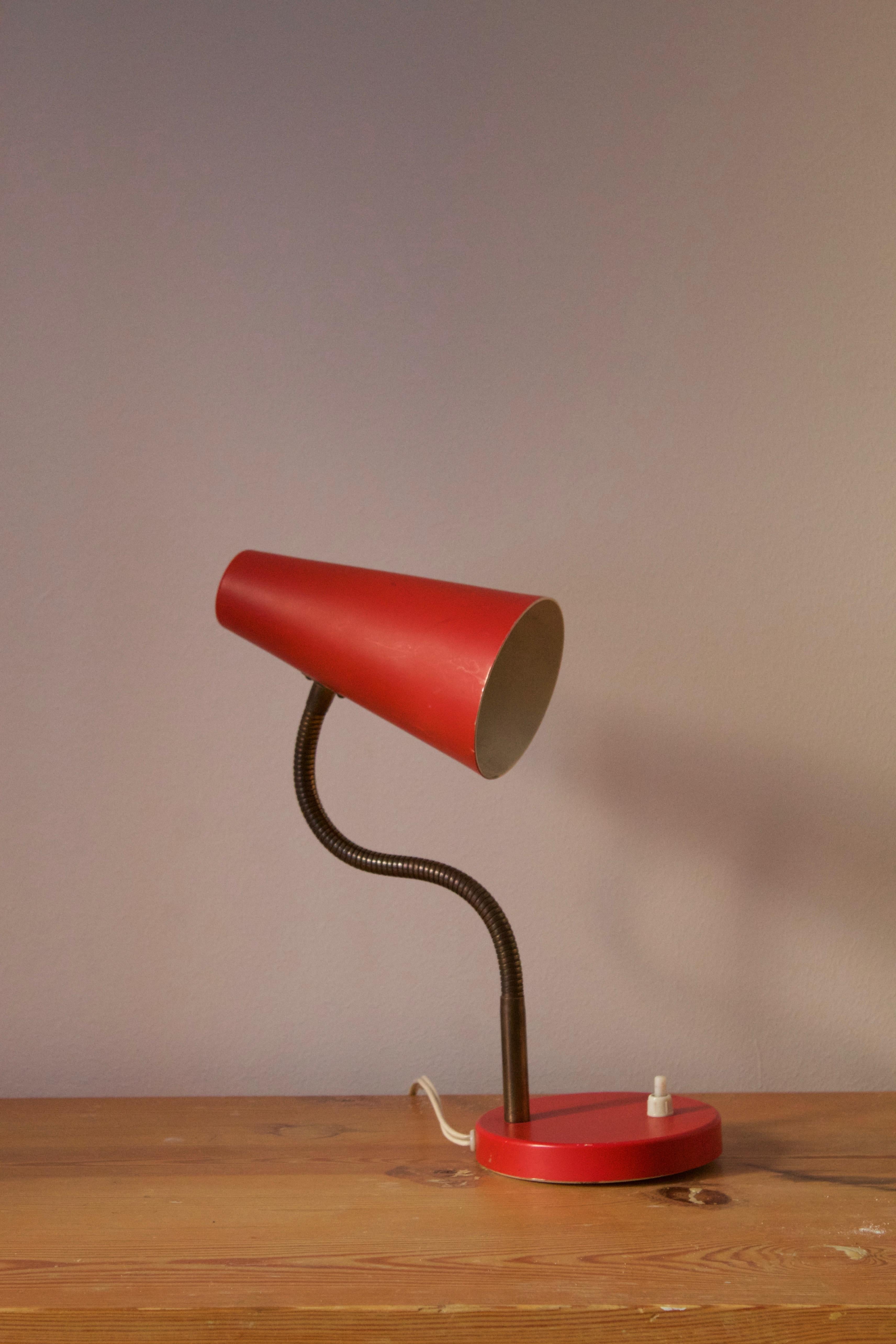 A table lamp / desk light, design is attributed to Svend Aage Holm Sørensen, Denmark, 1950s. Adjustable screen, original red lacquer. 

Other designers of the period include Paavo Tynell, Serge Mouille, Josef Frank, Angelo Lelii, and Lisa