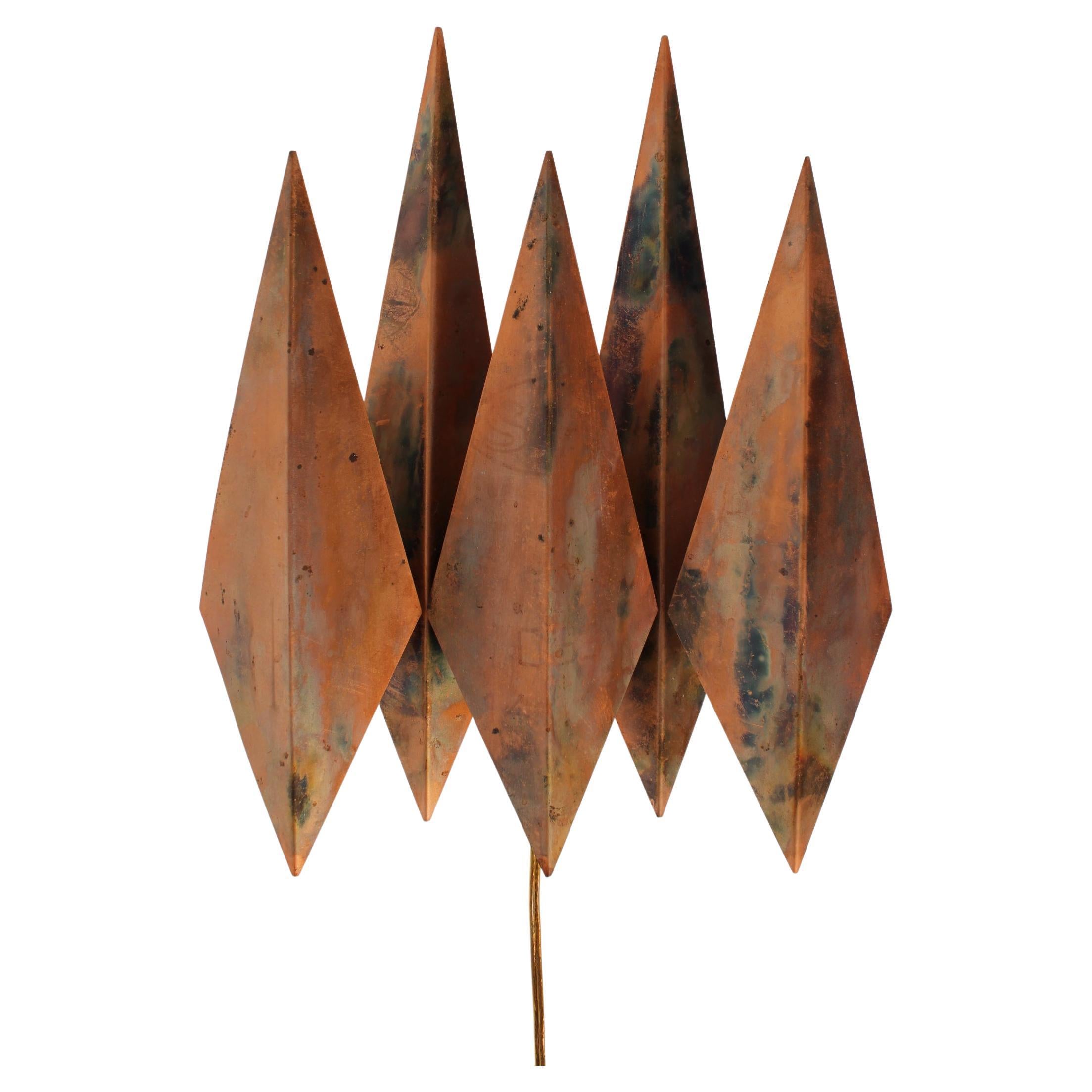 Applique/lampe torche danoise de style brutaliste conçue par Svend Aage Holm Sørensen et fabriquée par son propre atelier Holm Sørensen & Co.

Il est réalisé dans les années 1970 à partir de 5 boucliers pointus en cuivre patiné montés sur un socle