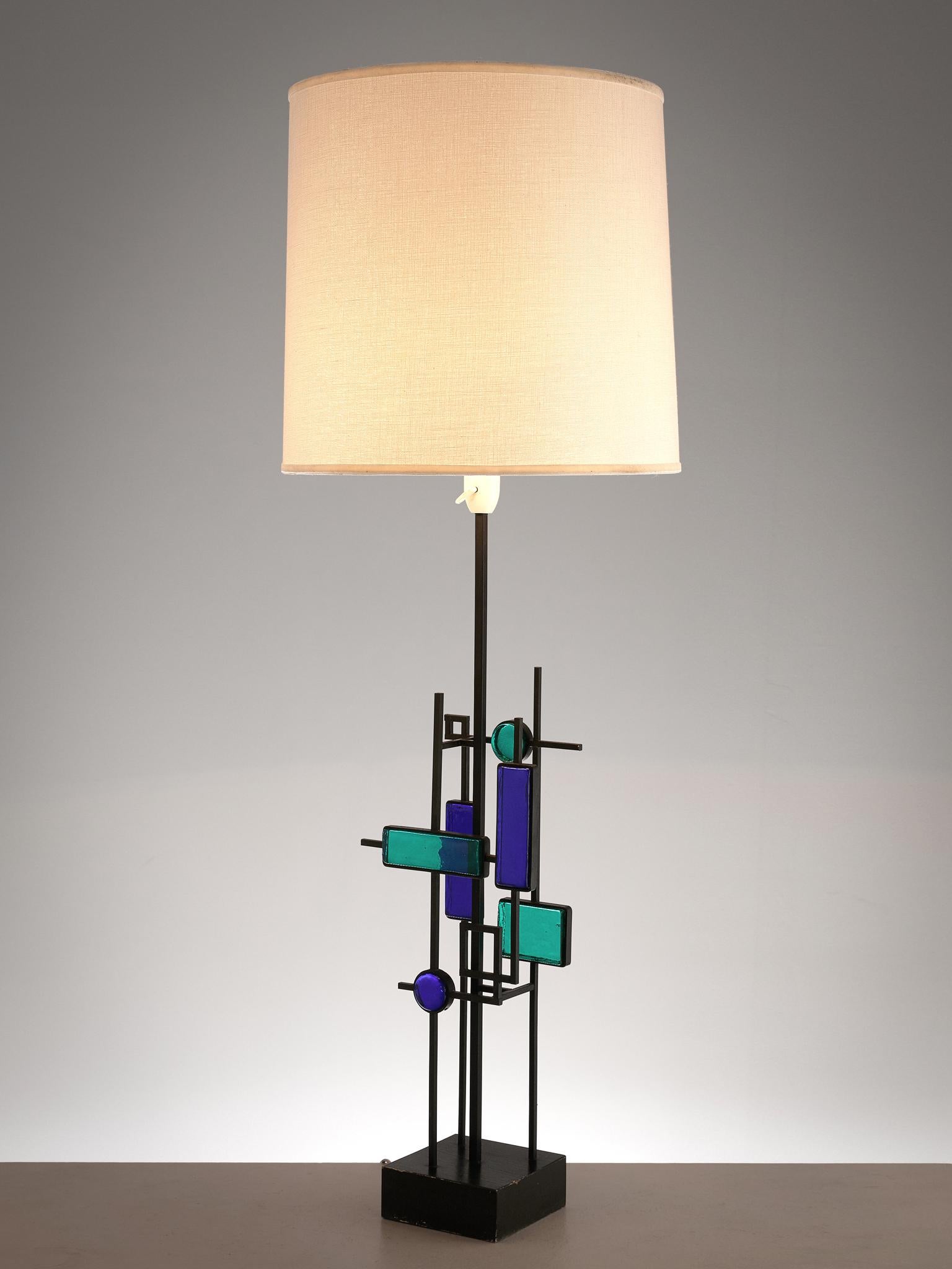 Svend Aage Holm Sørensen, table lamp, iron, wood and glass, Sweden, 1960s

A Brutalist table lamp by the Swedish Holm Sørensen, featuring an iron frame that holds several squares of glass in turquoise and blue. Above the glass shapes is the light