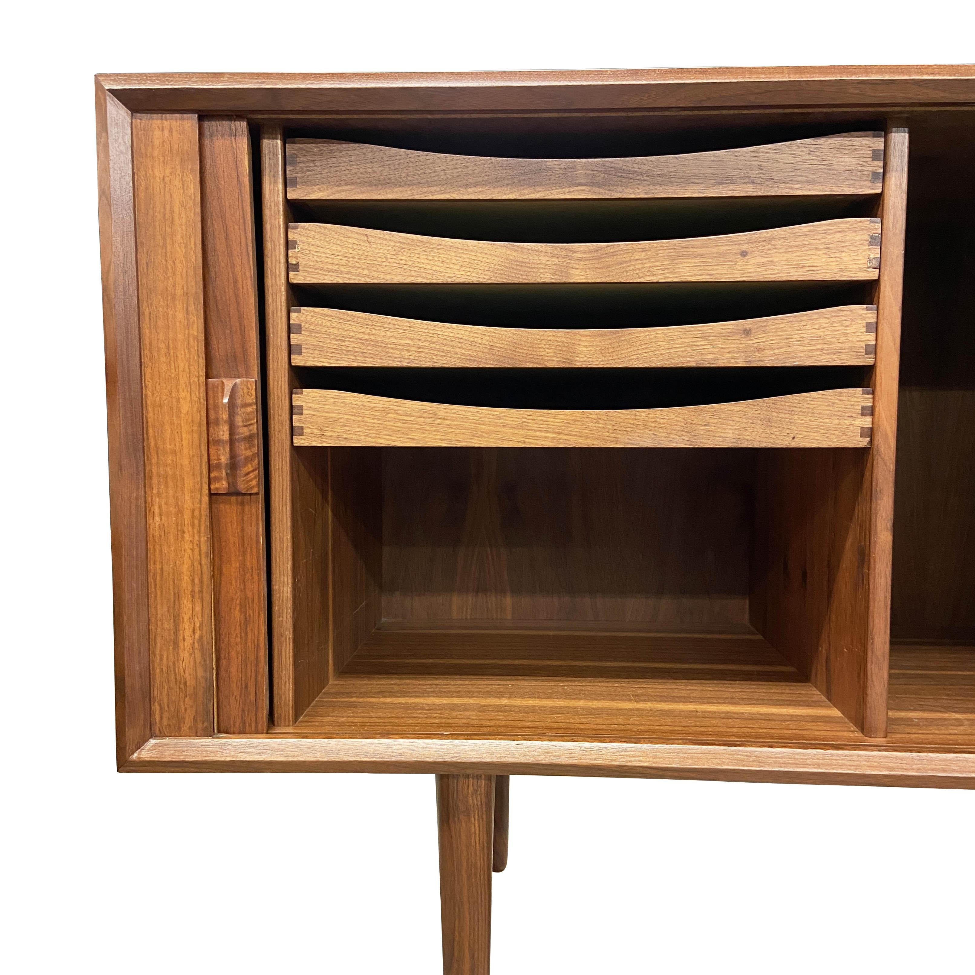 Expertly refinished teak credenza in superb condition featuring tambour style sliding doors and four pull out drawers, which are lined with felt. Designed by Svend Aage Larsen, this handsome 1960's piece sits on four sculpted wood legs. Beautiful