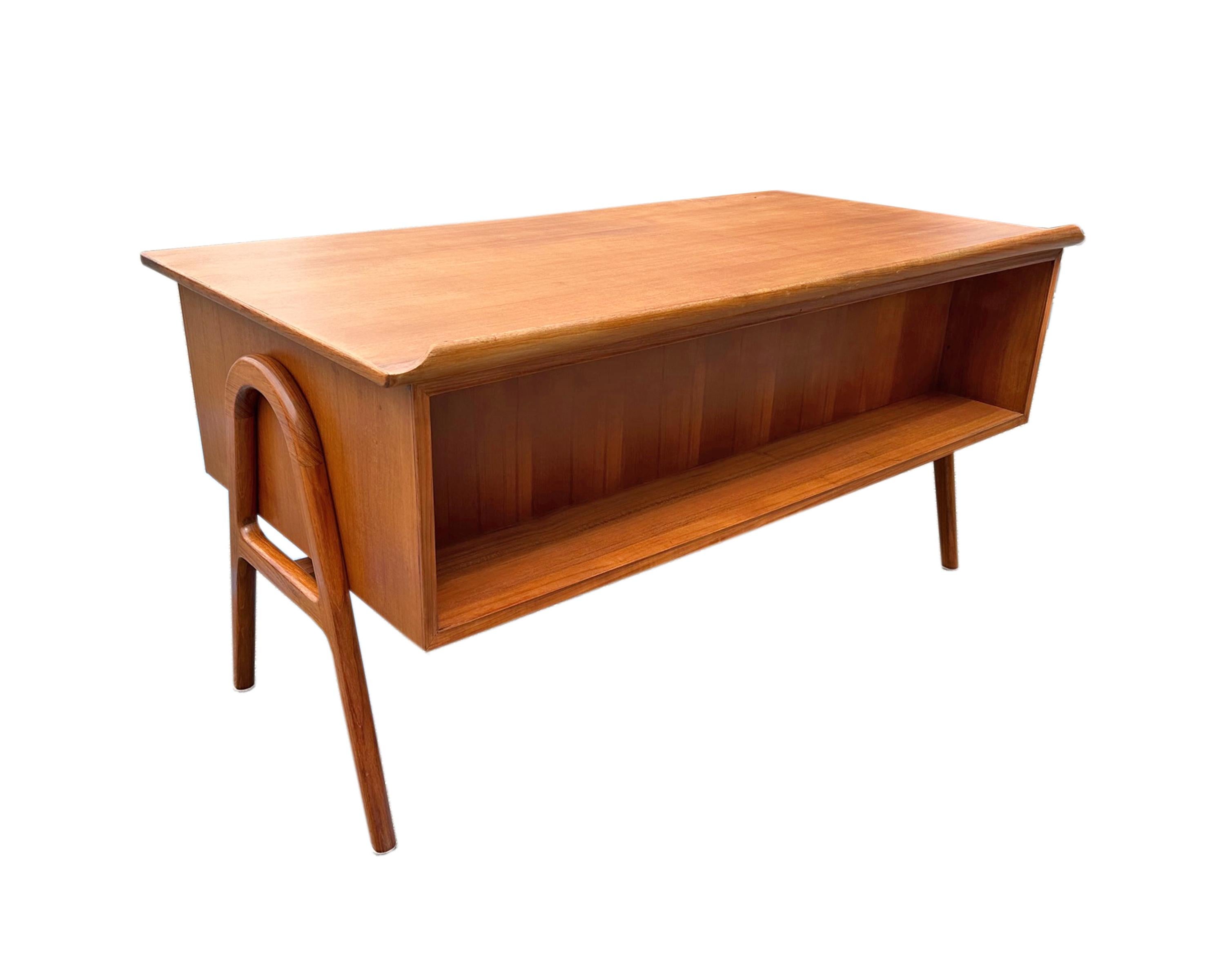A 1960s modern SH 180 desk designed by Svend Aage Madsen for Sigurd Hansen. Made of teak, this desk has three drawers on the right and a single large filed drawer on the left. The front of the desk has a bookshelf nook and the entire desk stands on