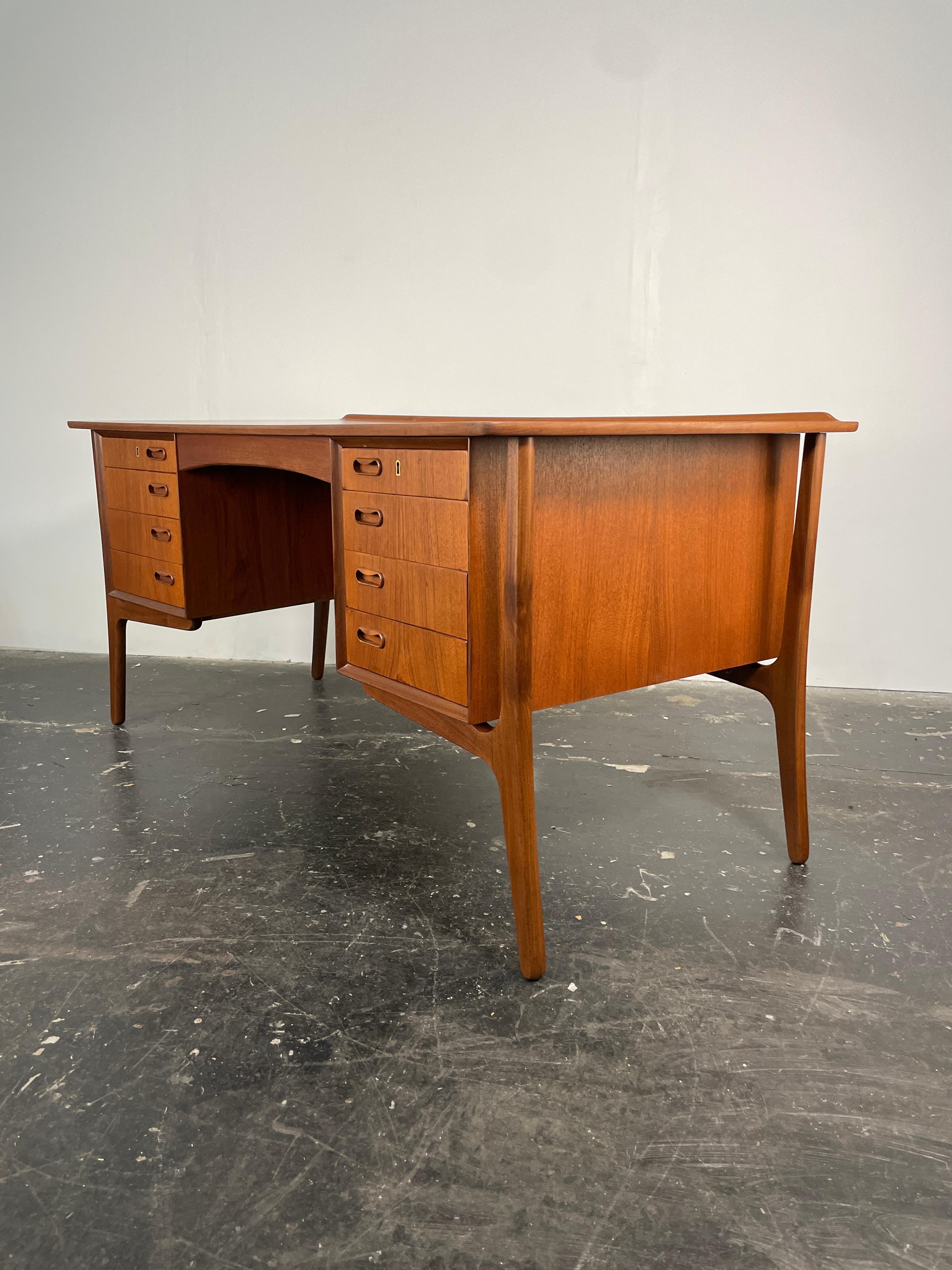 This is a beautifully curved front teak desk designed by Sven Aage Madsen. Incrediably elegant, this desk features beautiful tapered exoskeleton legs in Afromosia (African teak). Drawers grace both sides and offer plenty of storage. On the back side