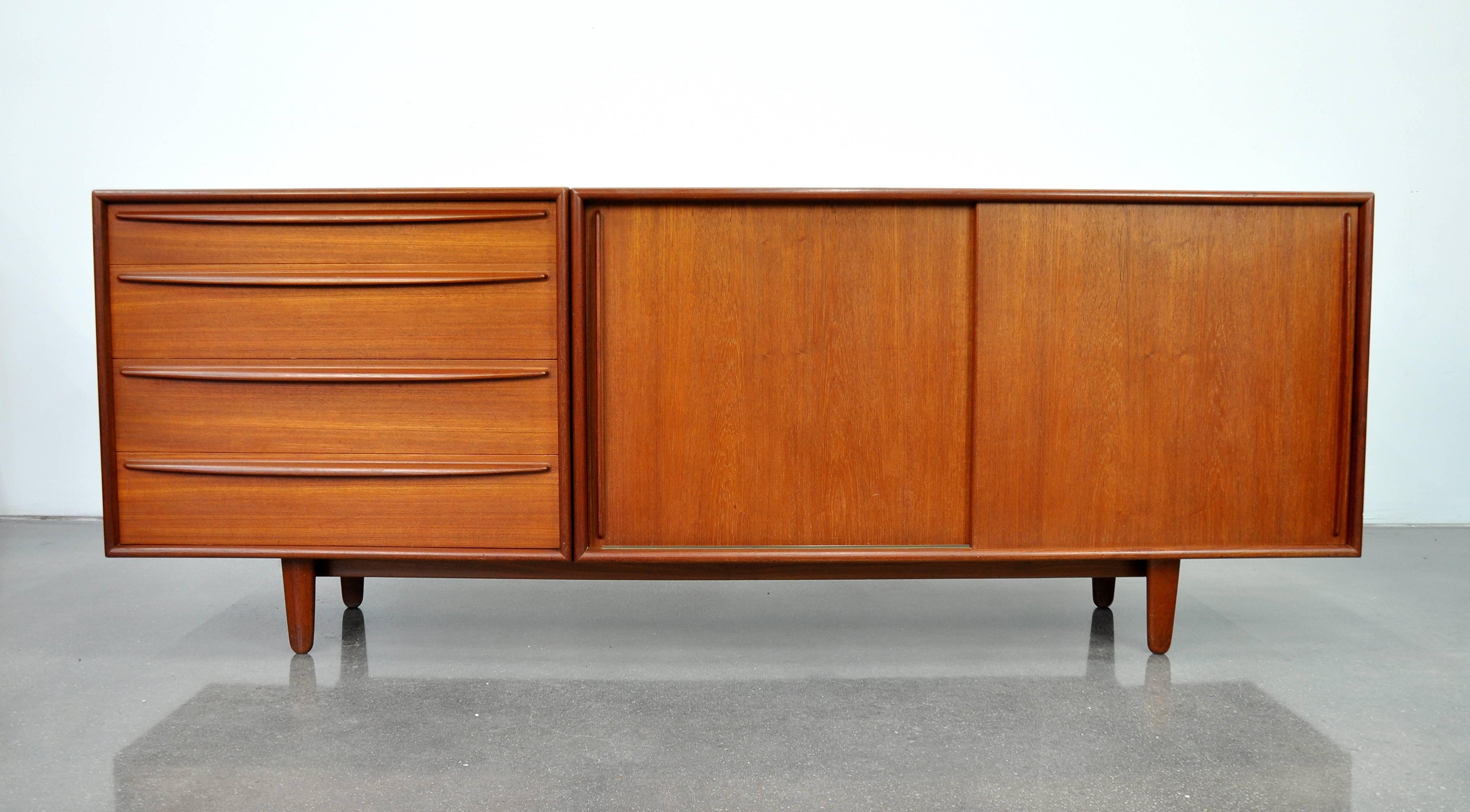 Beautiful Mid-Century Danish Modern teak bar cabinet, designed by Svend Madsen for Falster, made in Denmark in the 1960s. The sideboard features two sliding doors opening to an interior fitted with two shelves and a felt-lined drawer, and a dresser