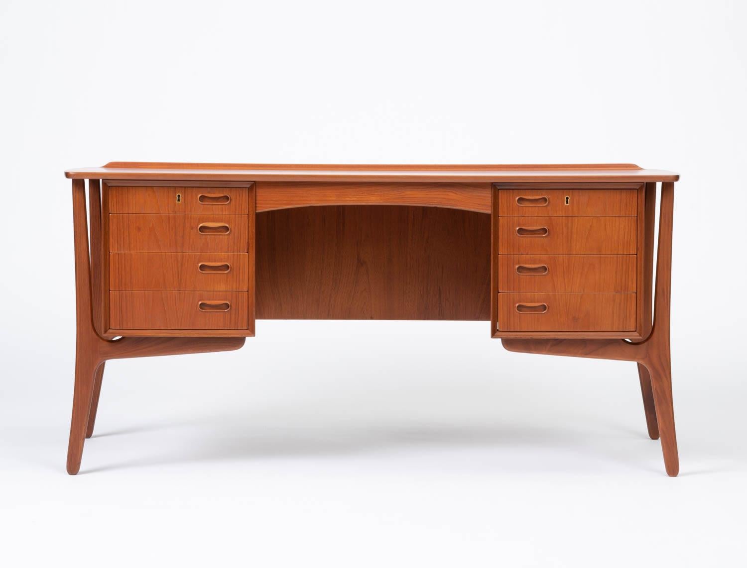 Classic Danish teak executive desk with twin drawer stacks and a broad writing surface. This piece, designed by Svend Åage Madsen for H.P. Hansen's Møbelindustri is distinguished by the bookcase that runs lengthwise along its back panel and the