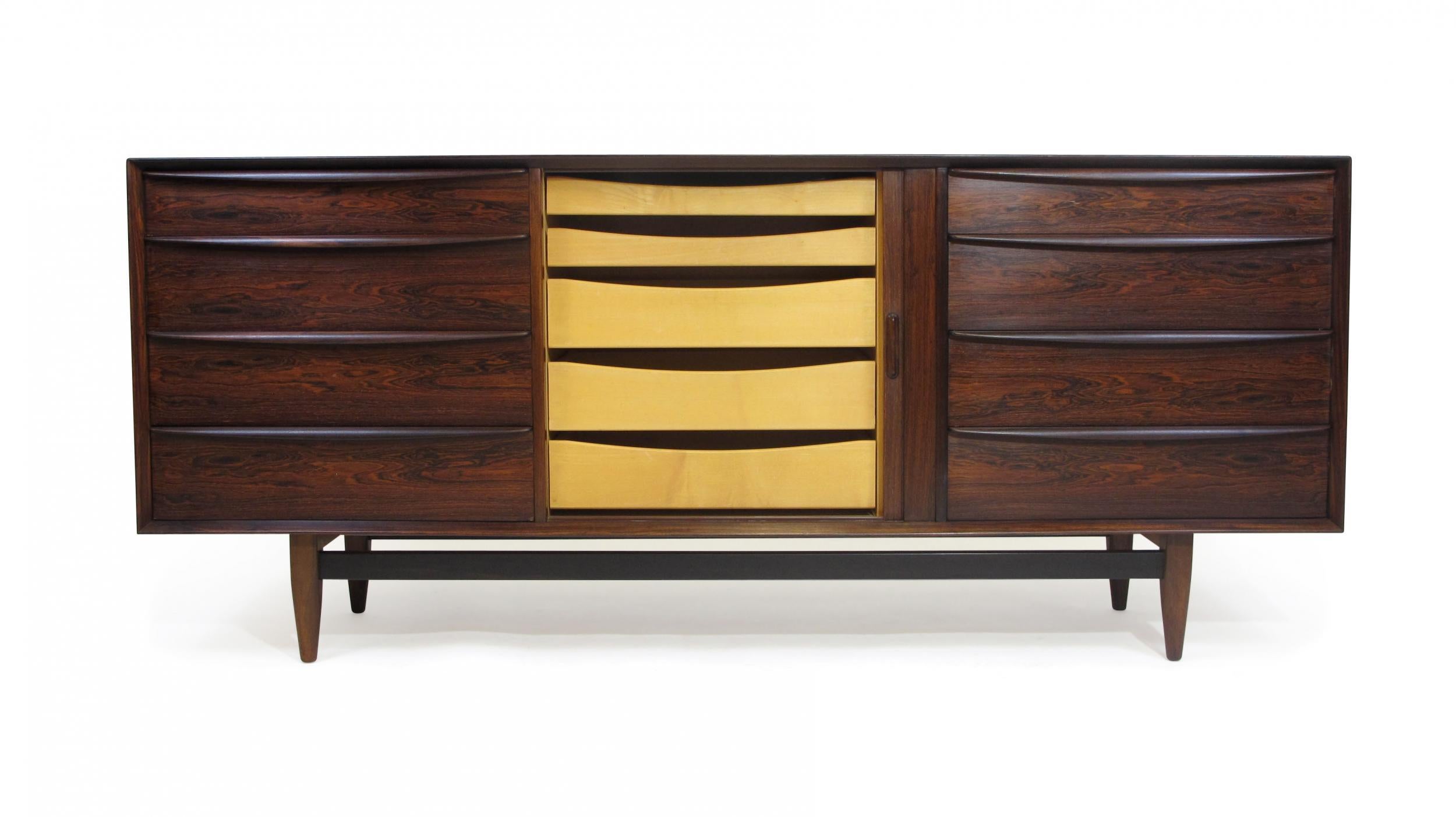 Mid century rosewood dresser credenza designed by Svend Age Madsen for Falster Mobelfabrik, Denmark. Crafted of old-growth dark rosewood with mitered corners, and raised on round tapered legs. The dresser has a total of 13 drawers. The left and