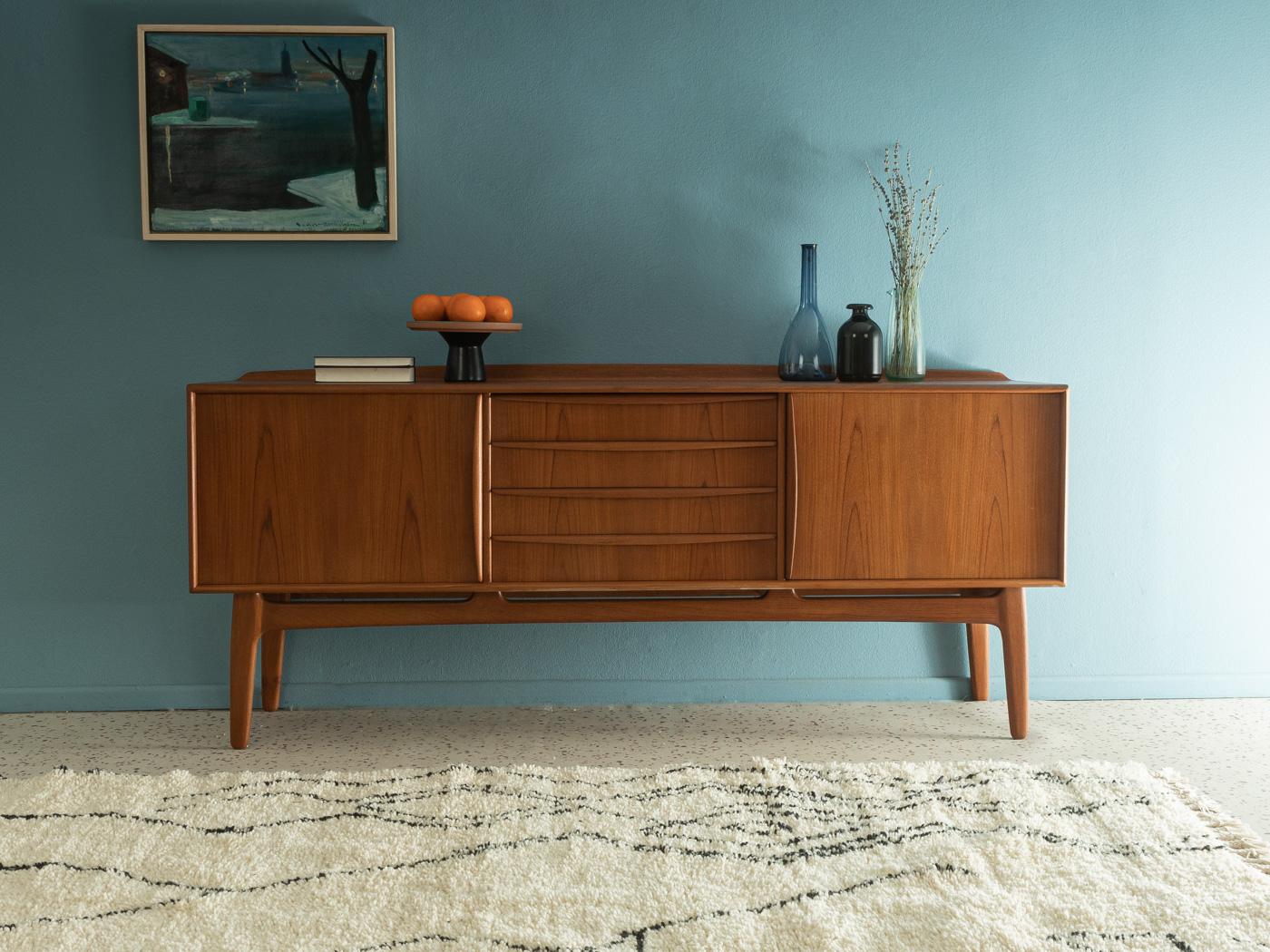 Classic sideboard from the 1960s by Svend Åge Madsen for Knudsen & Søn. Corpus in teak veneer with two sliding doors, two shelves, four drawers and slanted feet.

Quality Features:
- accomplished design: perfect proportions and visible attention