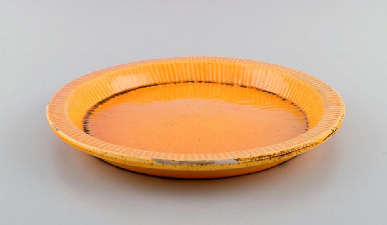 Svend Hammershøi for Kähler, HAK. 
Fluted dish in glazed stoneware. Beautiful yellow uranium glaze. 
1930s / 40s.
Measures: 25.5 x 2.5 cm.
Signed.
In excellent condition. A few glaze peels along the edge.