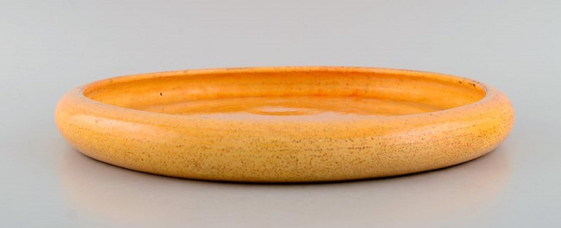 Svend Hammershøi for Kähler, HAK. Large round dish in glazed stoneware. 
Beautiful yellow uranium glaze. 1930s / 40s.
Measures: 29 x 3.3 cm.
Stamped.
In excellent condition.
