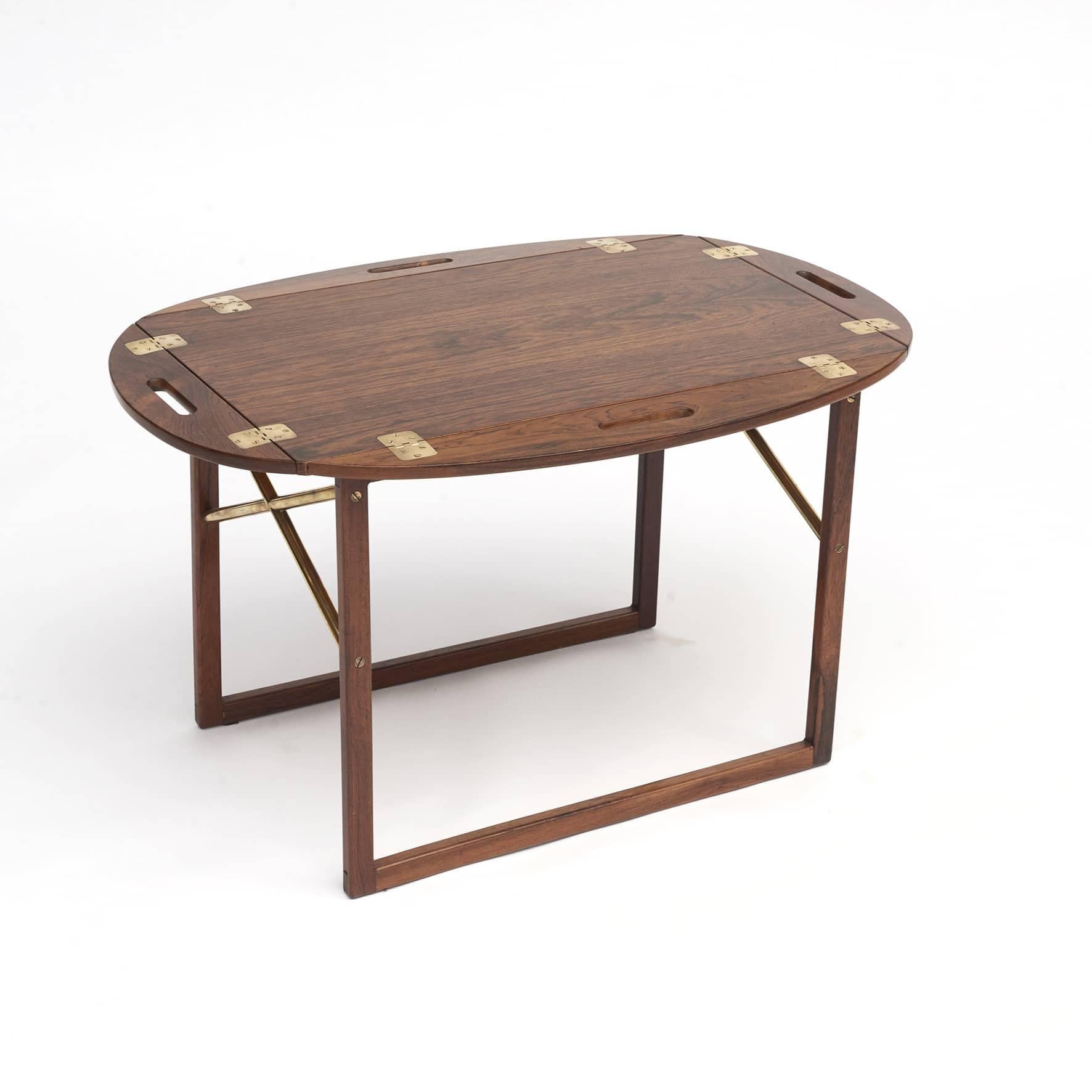 Svend Langkilde butler's tray table in hardwood, with brass fittings.
Between leg cross struts in brass.
Table top can be lifted off, with foldable sides up and down.
Measures unfolded H: 58, W: 74, D: 47.

Made in the 1960s for Illum