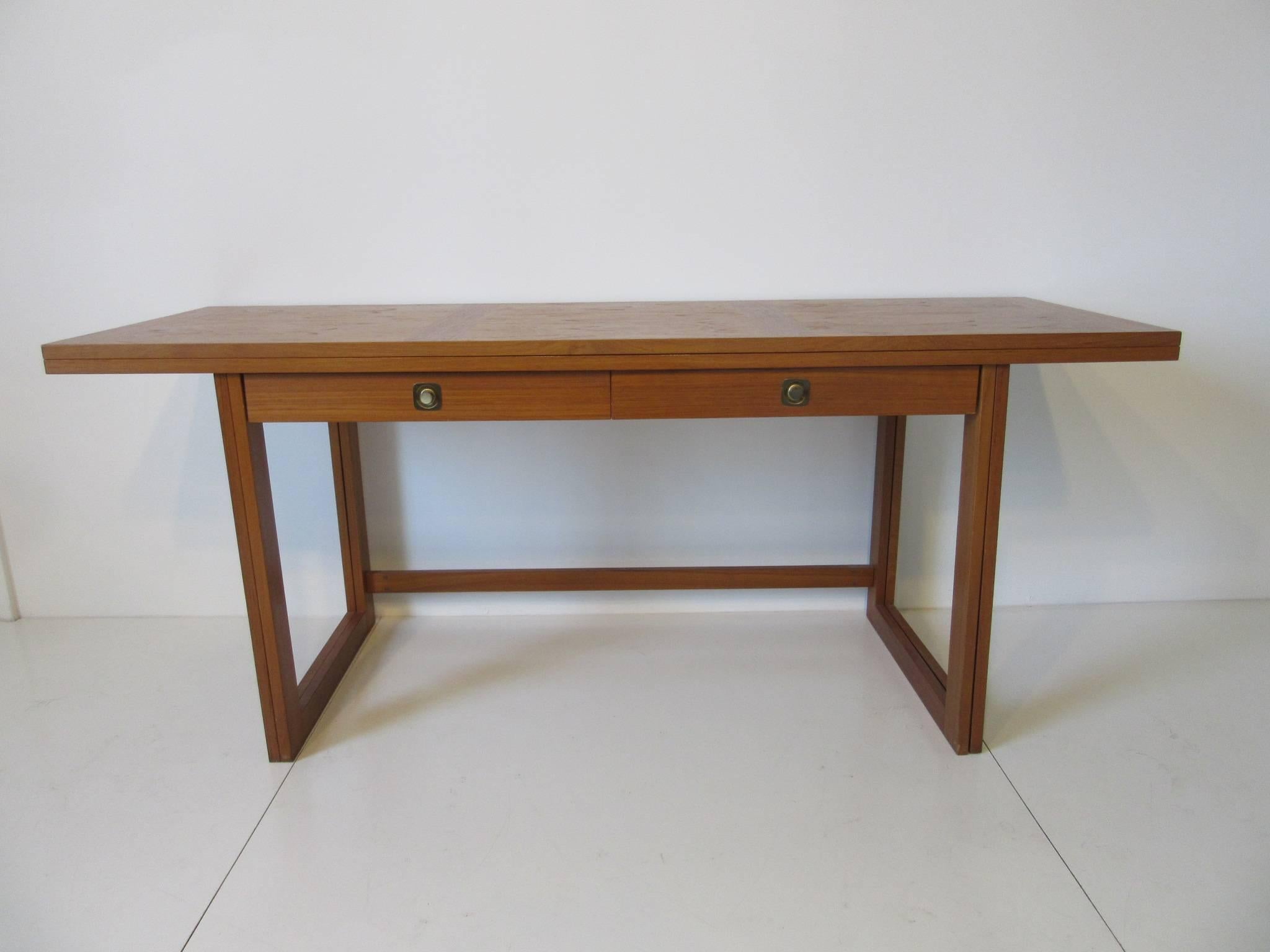 A creatively designed teak wood piece of furniture, it can be a desk with two small drawers and swing out the double legs, flip the top and it converts into a large dining table or work table. Beautiful grained wood , brass hinges and pulls makes