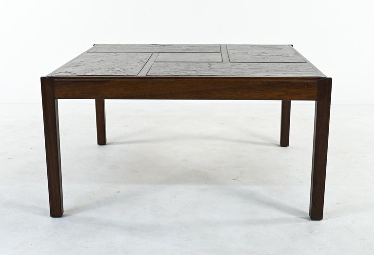A fabulous Scandinavian modern cocktail or coffee table in warm stained mahogany with an unusual inset slate top, sectioned into geometric rectangle tiles with texture and rich tones of bronze, gray, and umber. A transitional Brutalist piece, c.