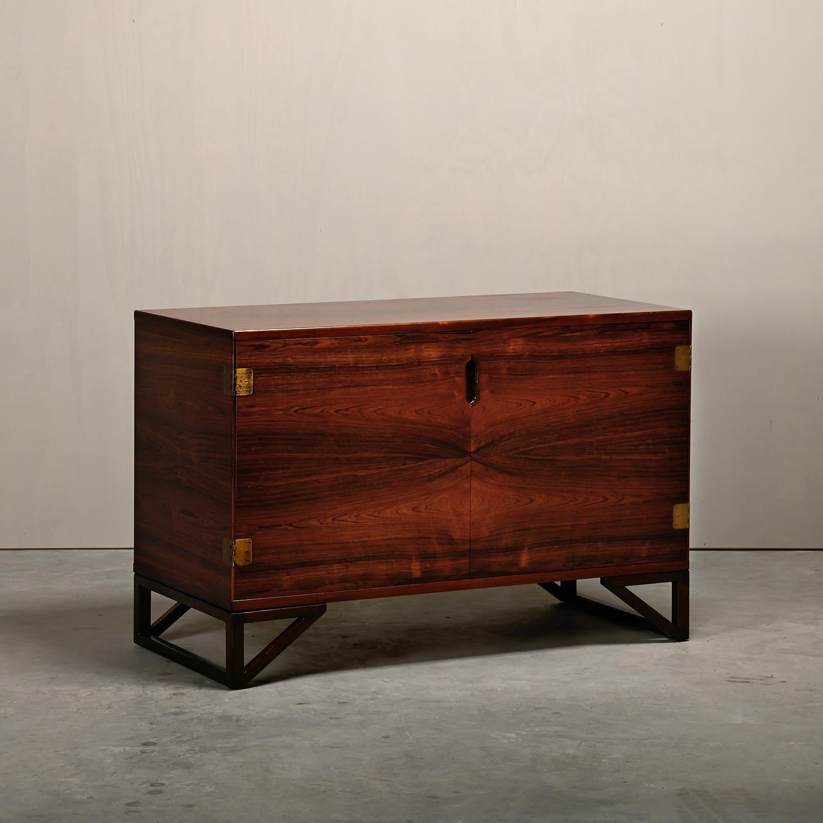 Beautiful cabinet in rosewood desgined by Svend Langkilde for Illums Bolighus, Denmark 1960s. Two doors with brass hinges and an interior with shelves and one drawer that also can be used as tray. The exquisite rosewood veneer bookmatched on all