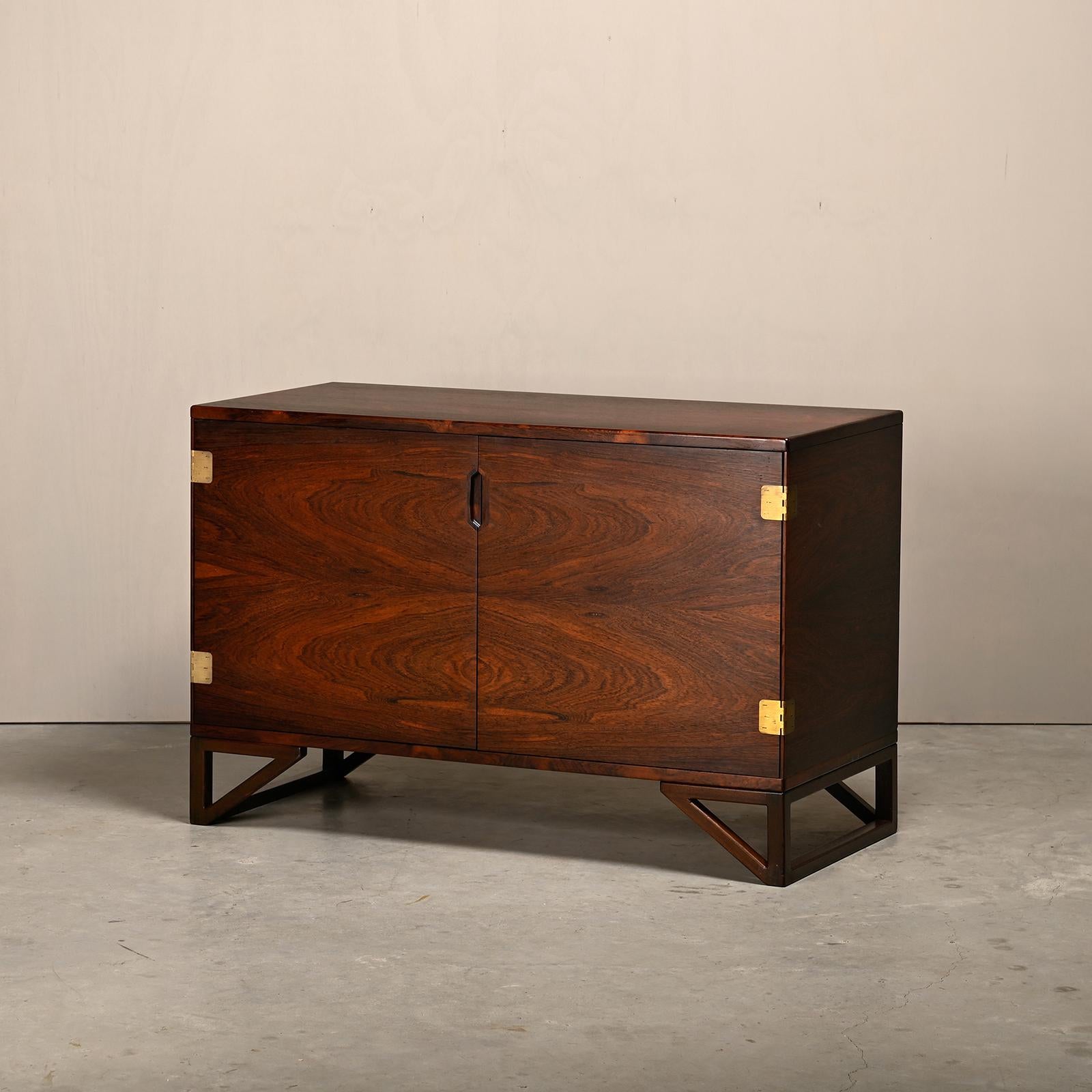 Bellissimo mobile in palissandro disegnato da Svend Langkilde per Illums Bolighus, Danimarca anni '60. Due ante con cerniere in ottone e un interno con due ripiani e quattro cassetti che possono essere utilizzati anche come vassoi. La squisita