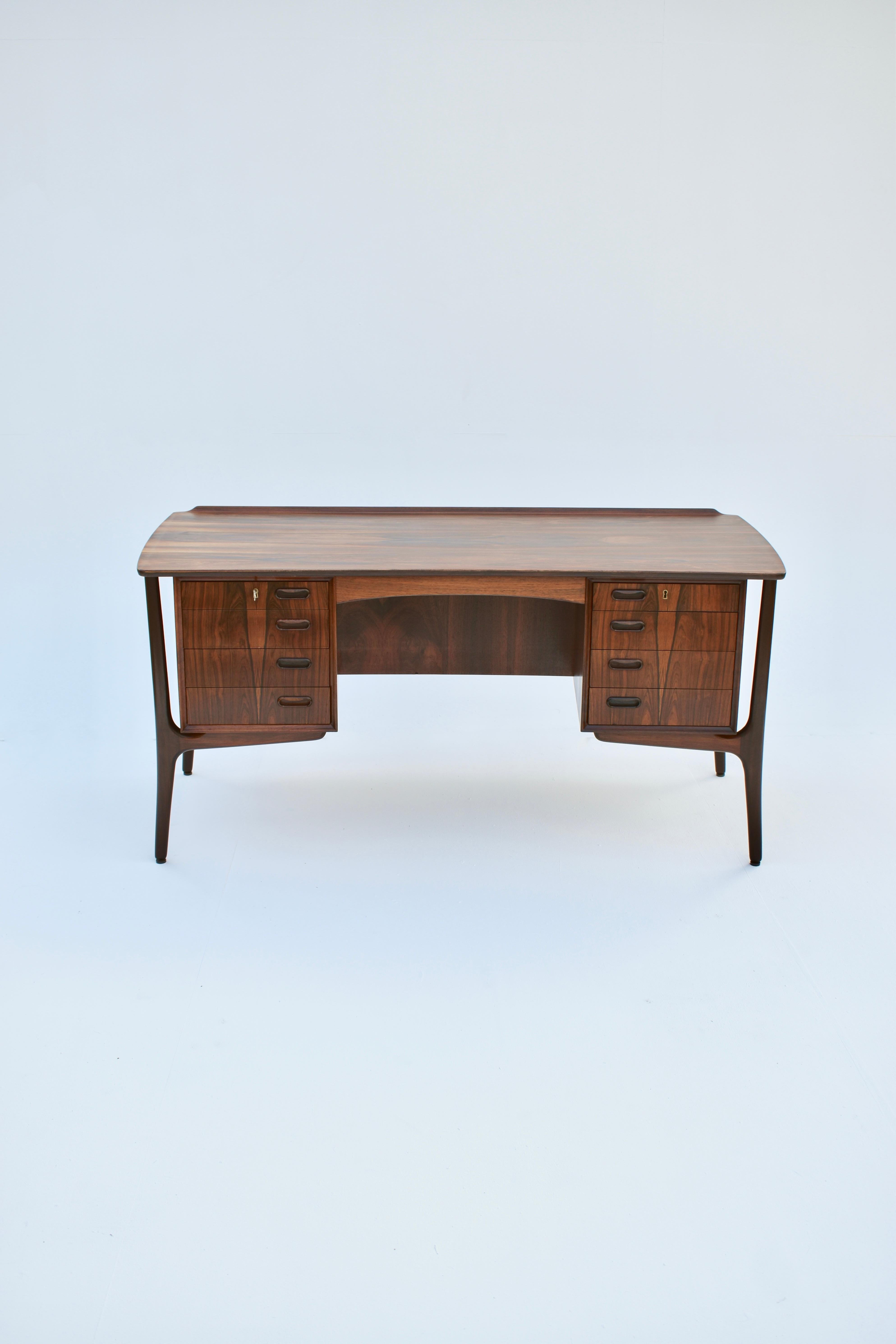 Spectacular double pedestal desk of the most elegant design executed in dramatic Brazilian rosewood. Featuring a beautiful curved desktop that wraps itself towards the sitter. To the opposite side of the surface a raised fin. Slender sculptural legs