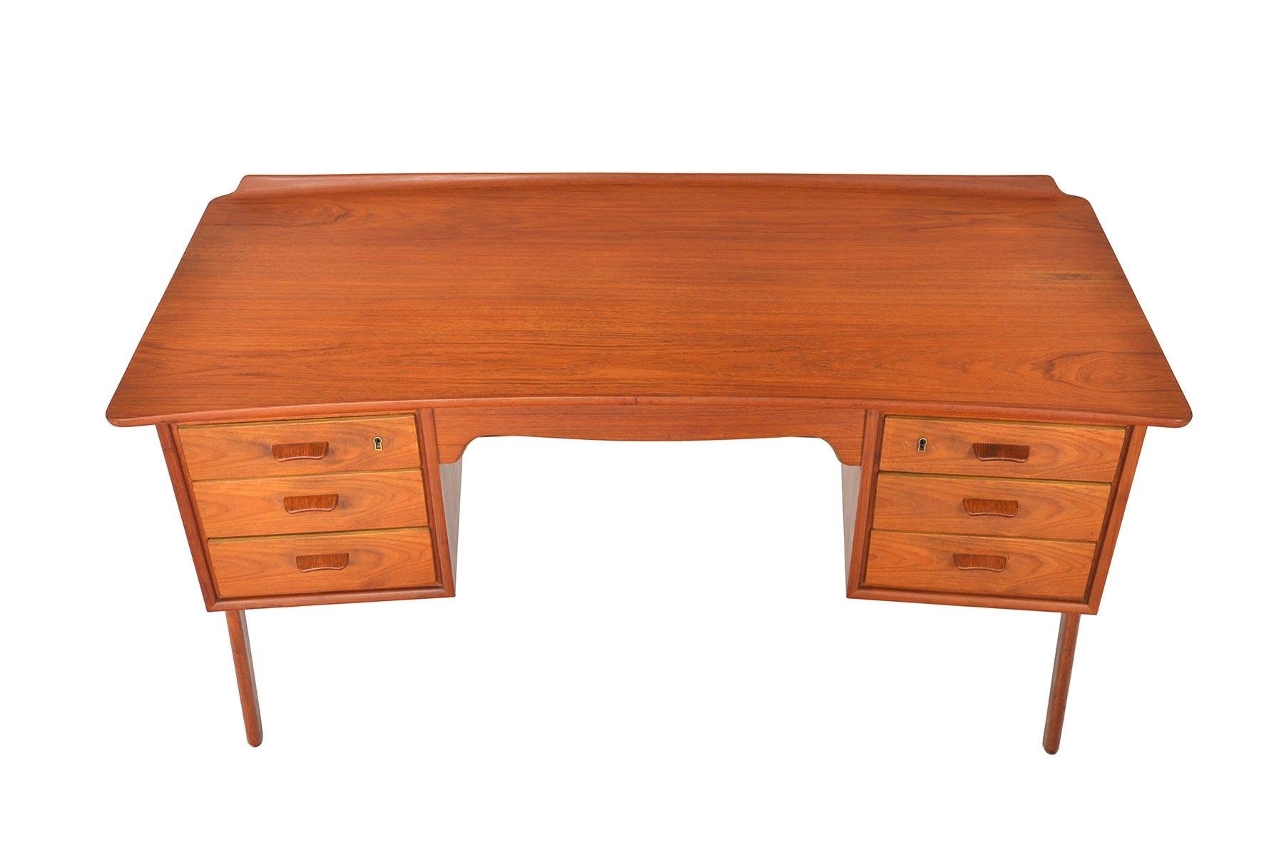 This gorgeous Danish modern model SH-180 executive desk was designed by Svend Madsen for Sigurd Hansen in the 1960s. Exterior mounted legs provide this piece a stunning atomic silhouette. Kneehole is flanked by two bays of three drawers. Finished