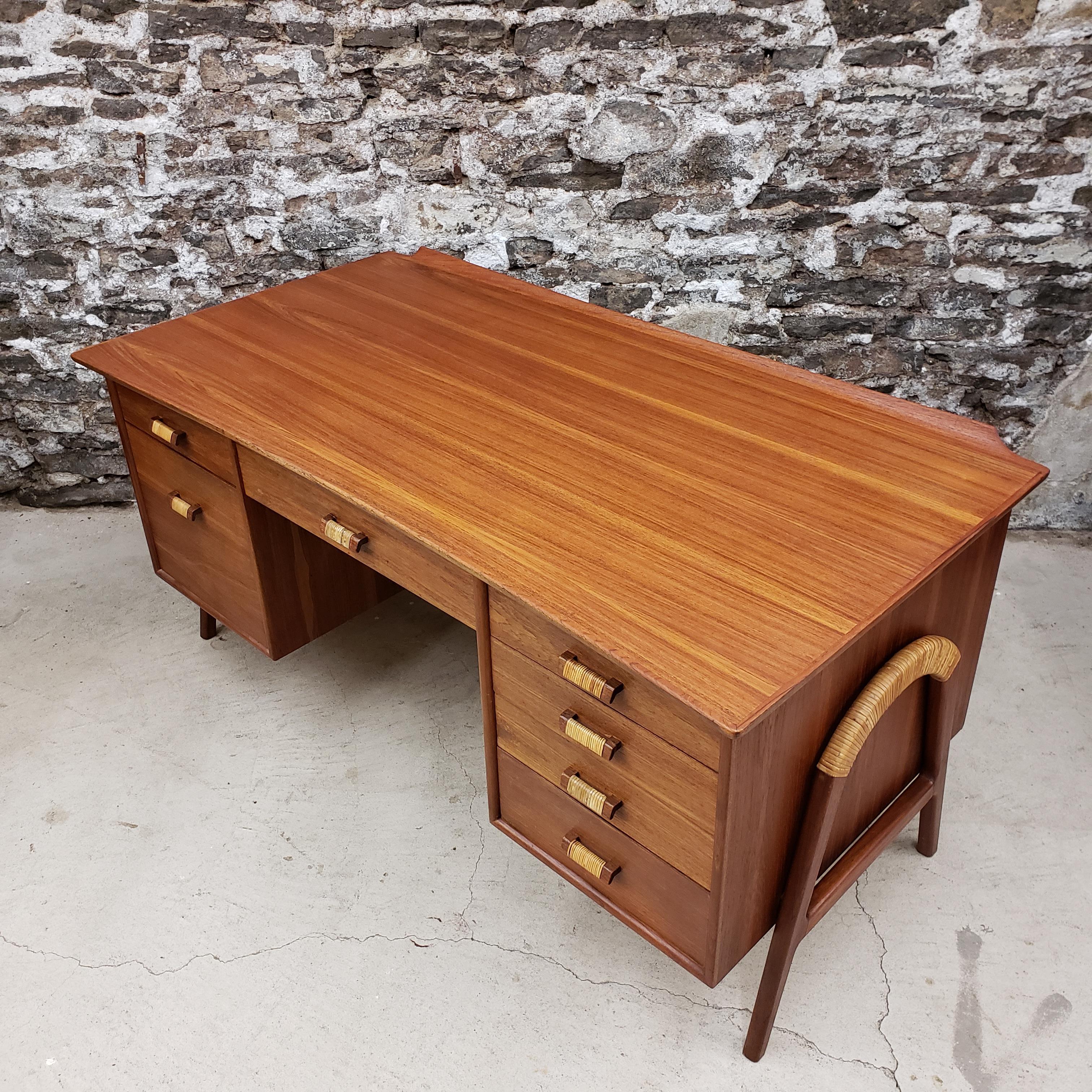 Danish Modern 'first edition' executive desk designed by Svend Aage Madsen. This Mid-Century Modern era writing desk features beautiful cane details on both the frame and handles. It has an elegant curved shape and is held up by two U shaped legs