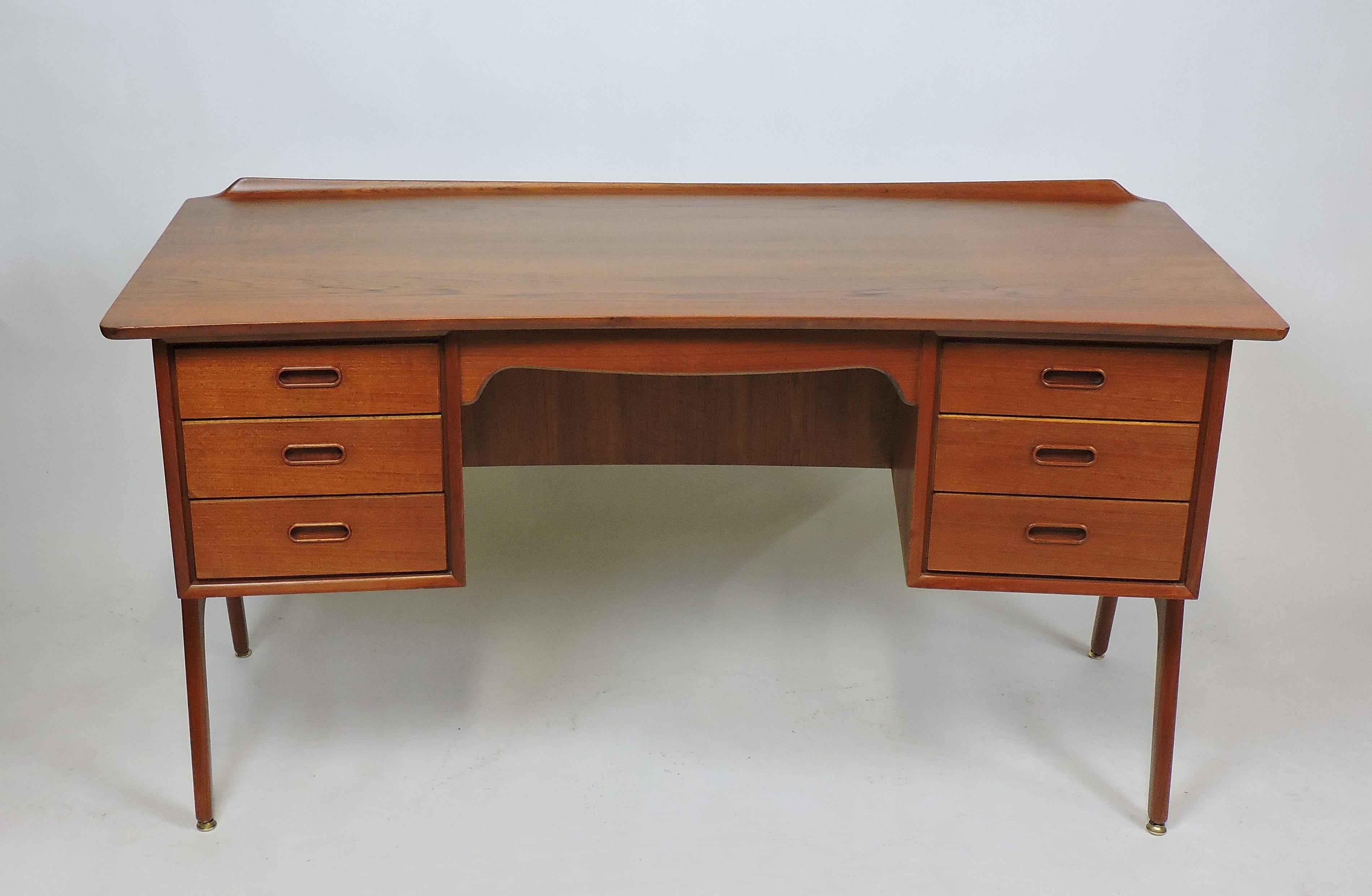 Beautiful sculptural teak desk, model SH 180, designed by Svend Aage Madsen and made in Denmark by Sigurd Hansens Mobelfabrik. This curved desk has six drawers, a large work space with a raised lip, and an open shelf in the front. Unique tapered