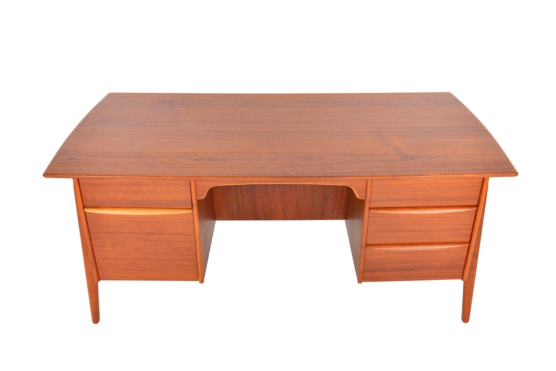 This gorgeous Danish modern executive desk was designed by Svend Madsen in the 1960s. Exterior mounted legs are canted to give this piece a stunning atomic silhouette. To the left of the kneehole is a pull out writing surface and file cabinet