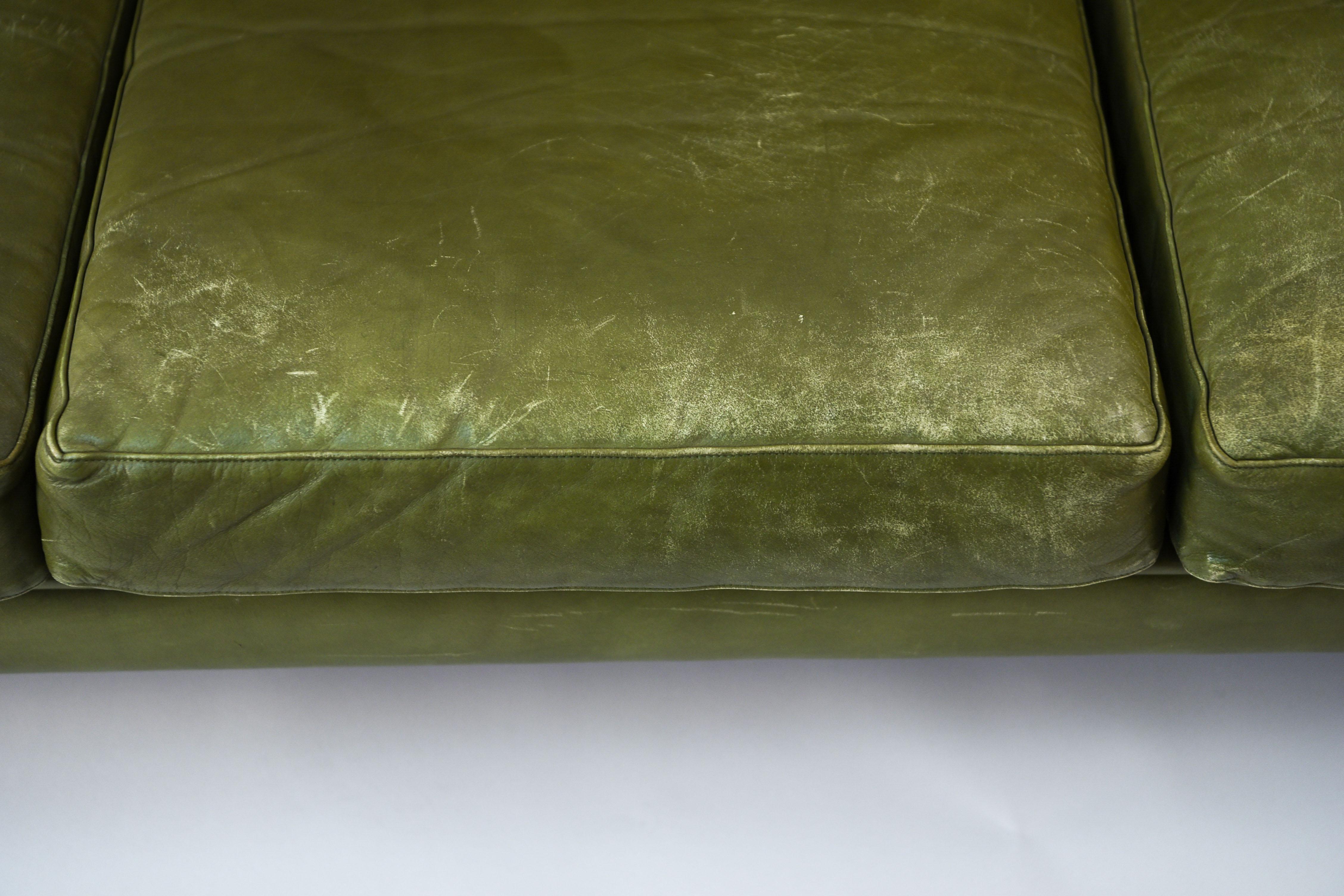 This Danish mid-century three-seat sofa was designed by Svend Skipper and manufactured by Skipper Mobler in the 1960s. It is upholstered in an unusual, attractive olive green leather with button tufted back cushions.