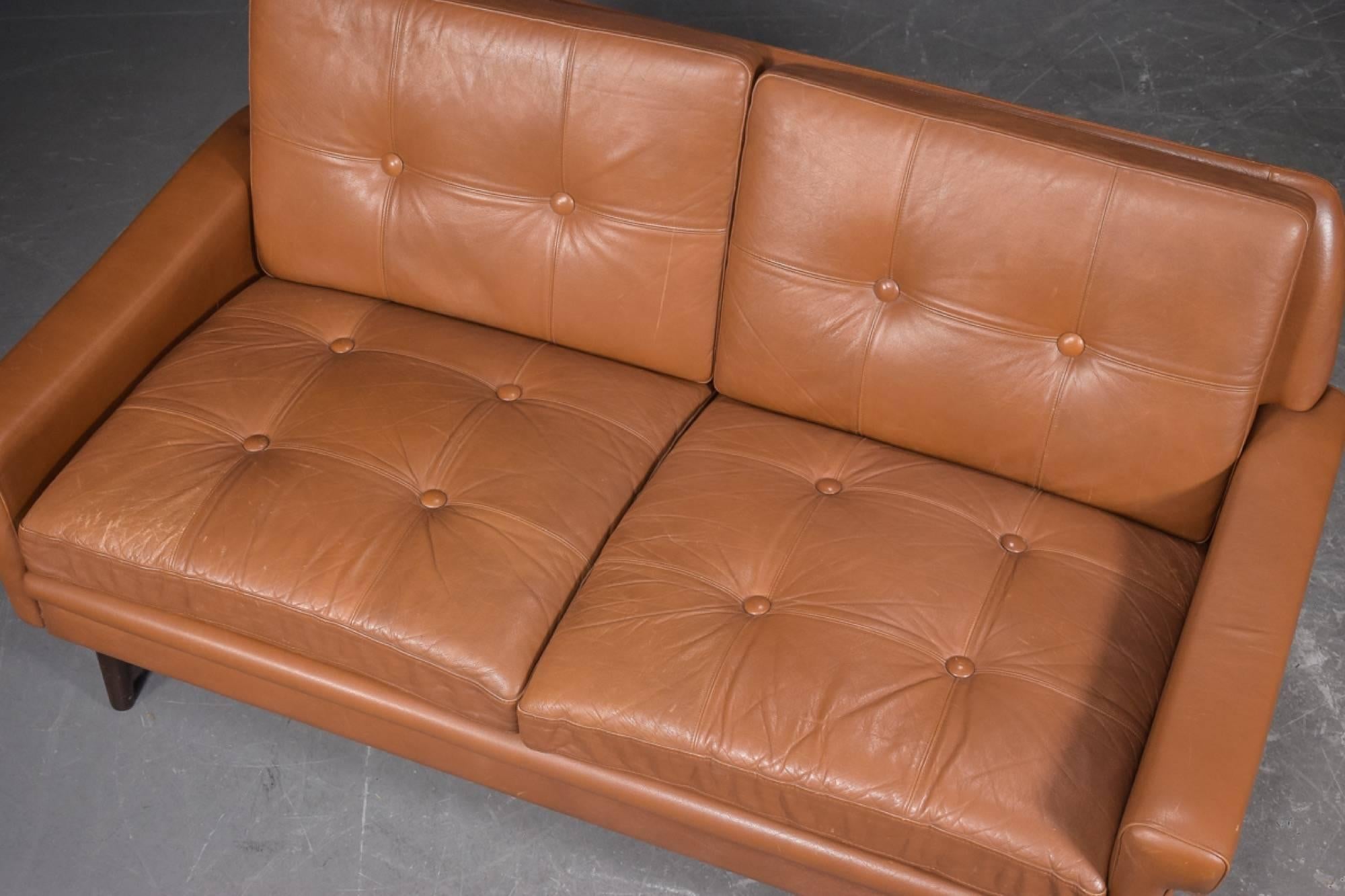 Svend Skipper loveseat sofa covered with brown leather, with round tapered teak legs.